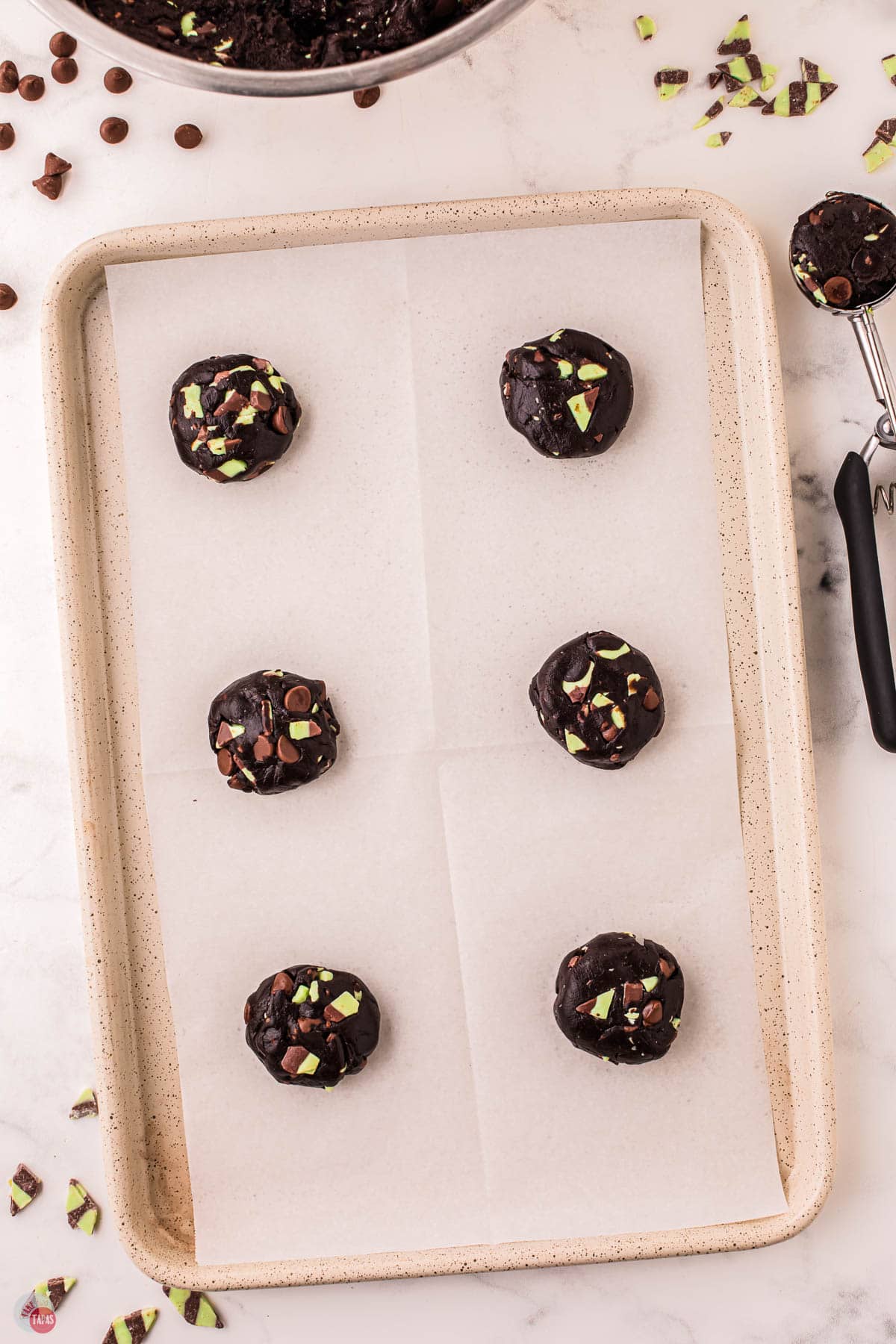 unbaked cookie dough balls on a baking sheet with parchment paper