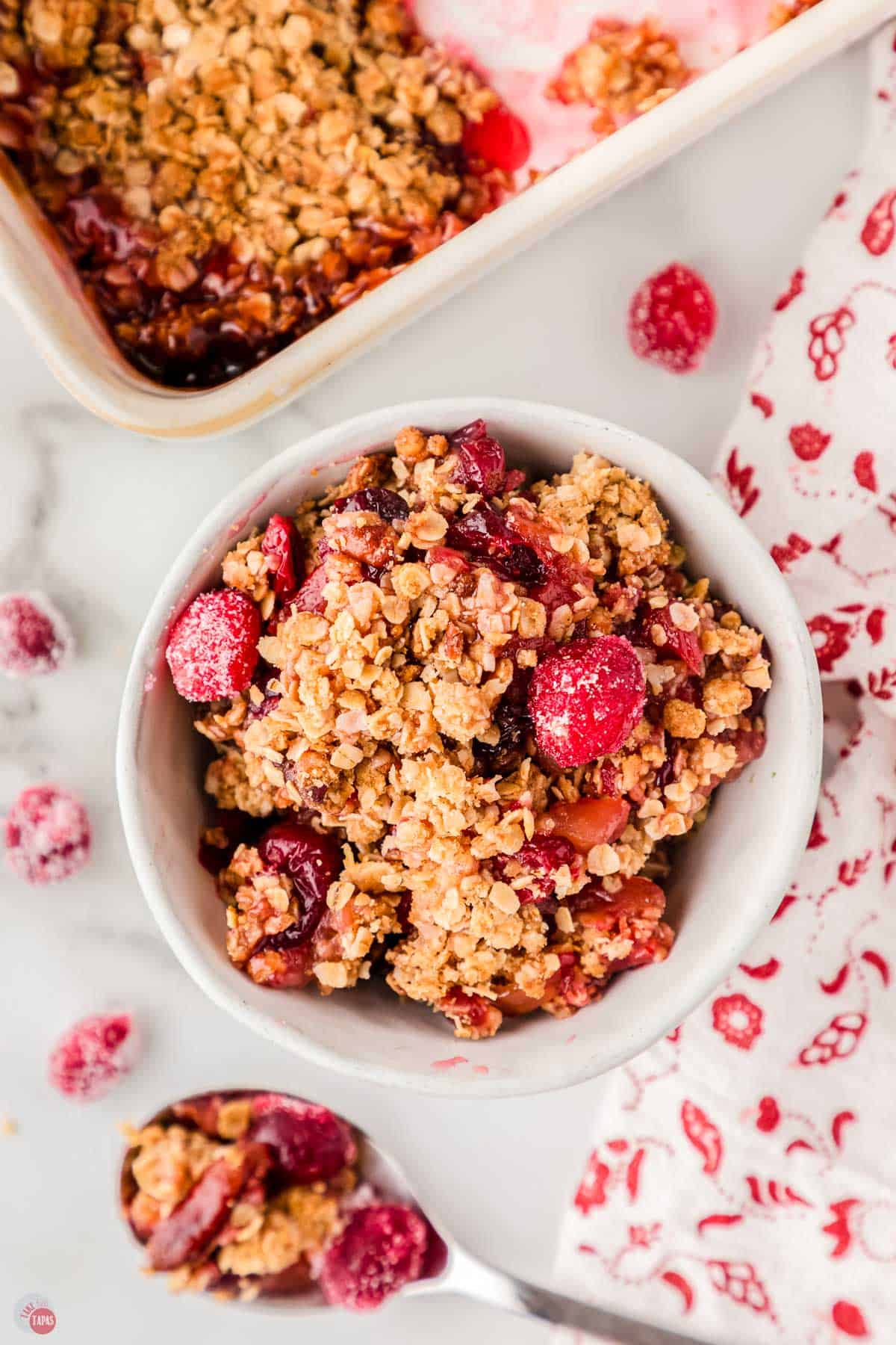 small white bowl filled with cranberry casserole with a red and white napkin next to it.