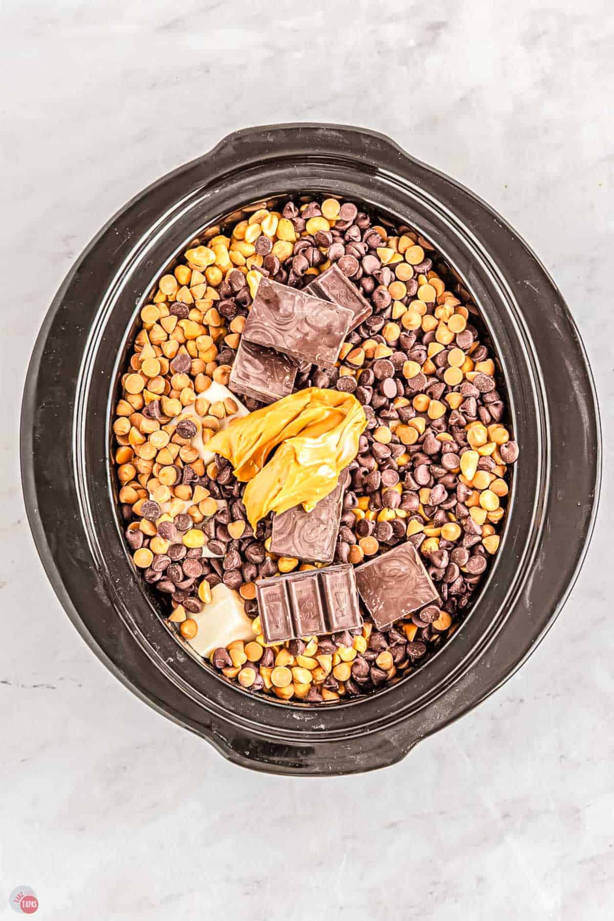 crockpot with peanuts, chocolate chips, and peanut butter in it