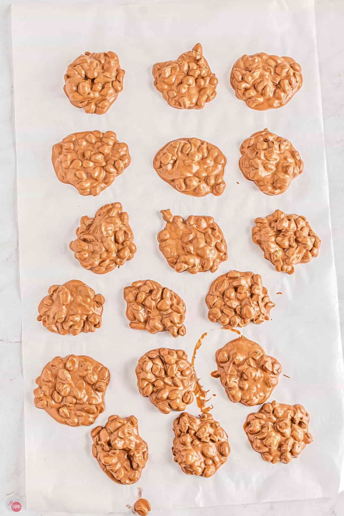 parchment paper with mounds of chocolate and peanuts on it