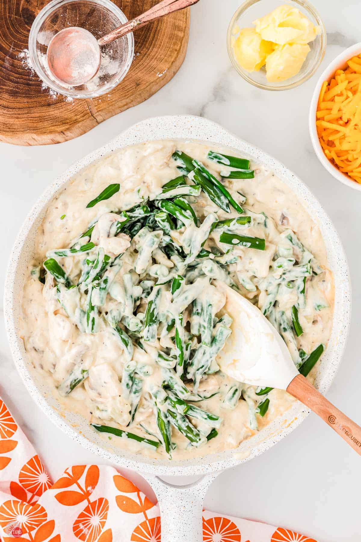 green beans being stirred into a sauce with a spatula