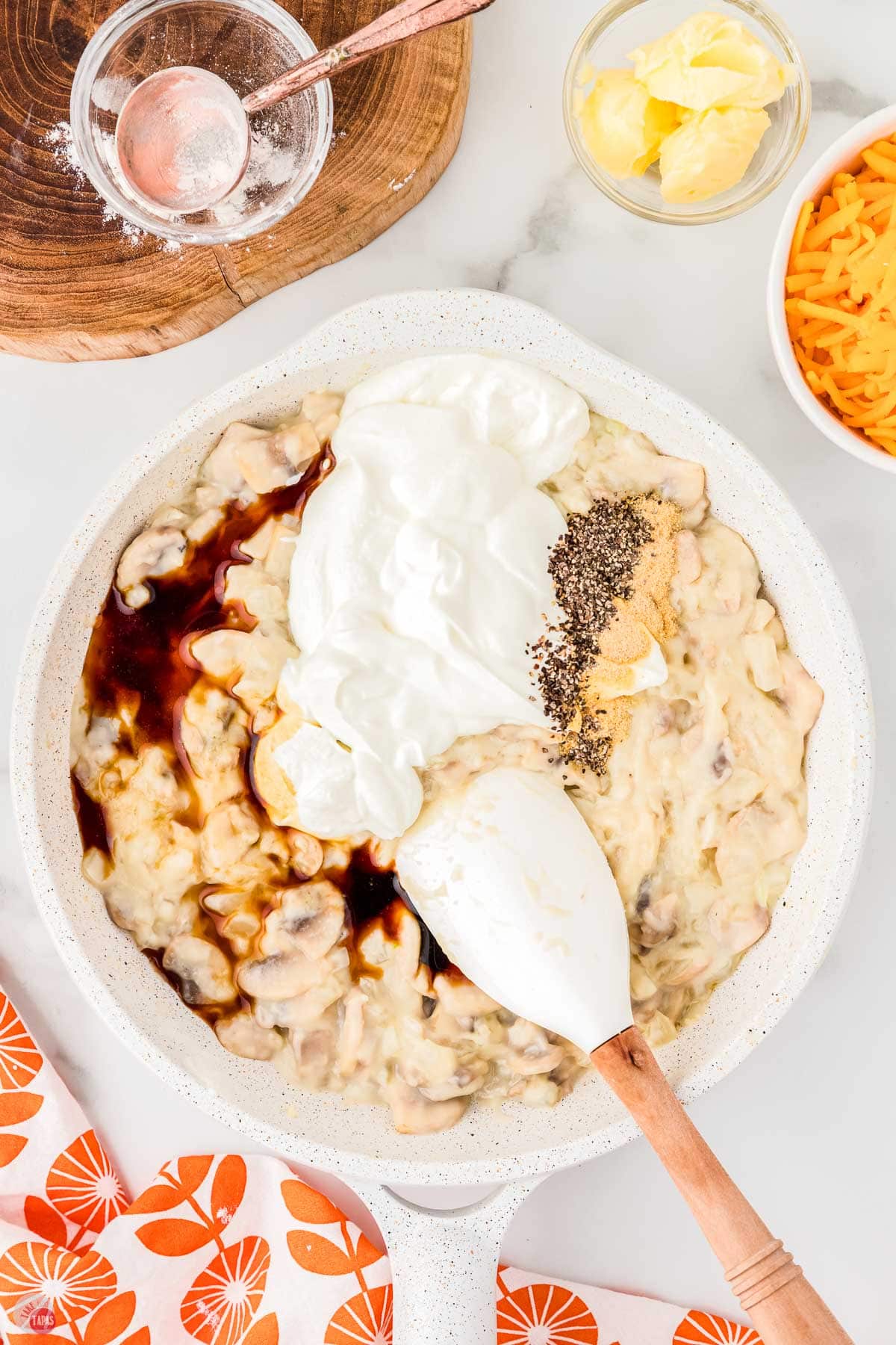 skillet with sour cream, spices, and mushrooms in it