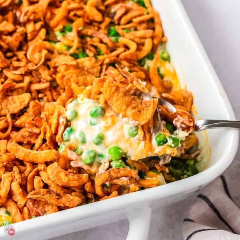 spoon scooping pea casserole out of a white dish
