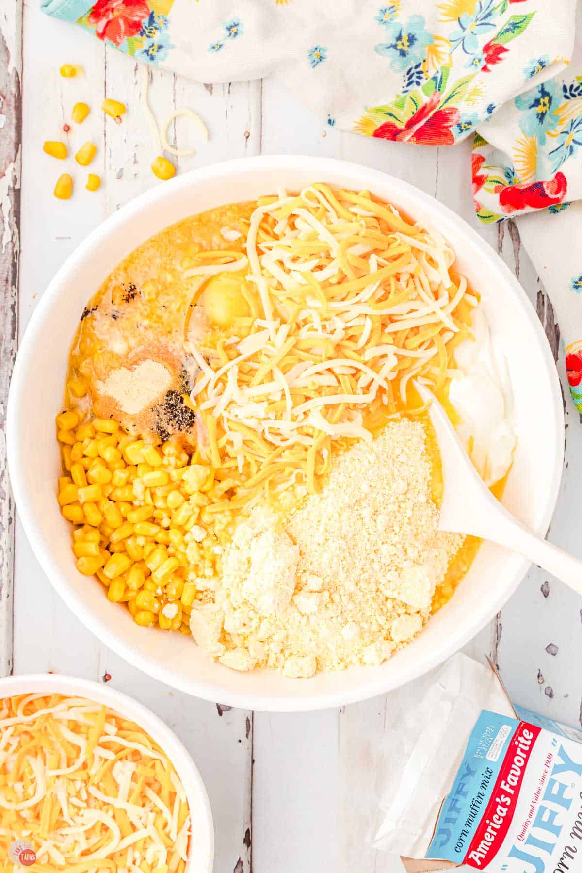corn, cheese, egg, and cornbread mixture in a white bowl with a spoon