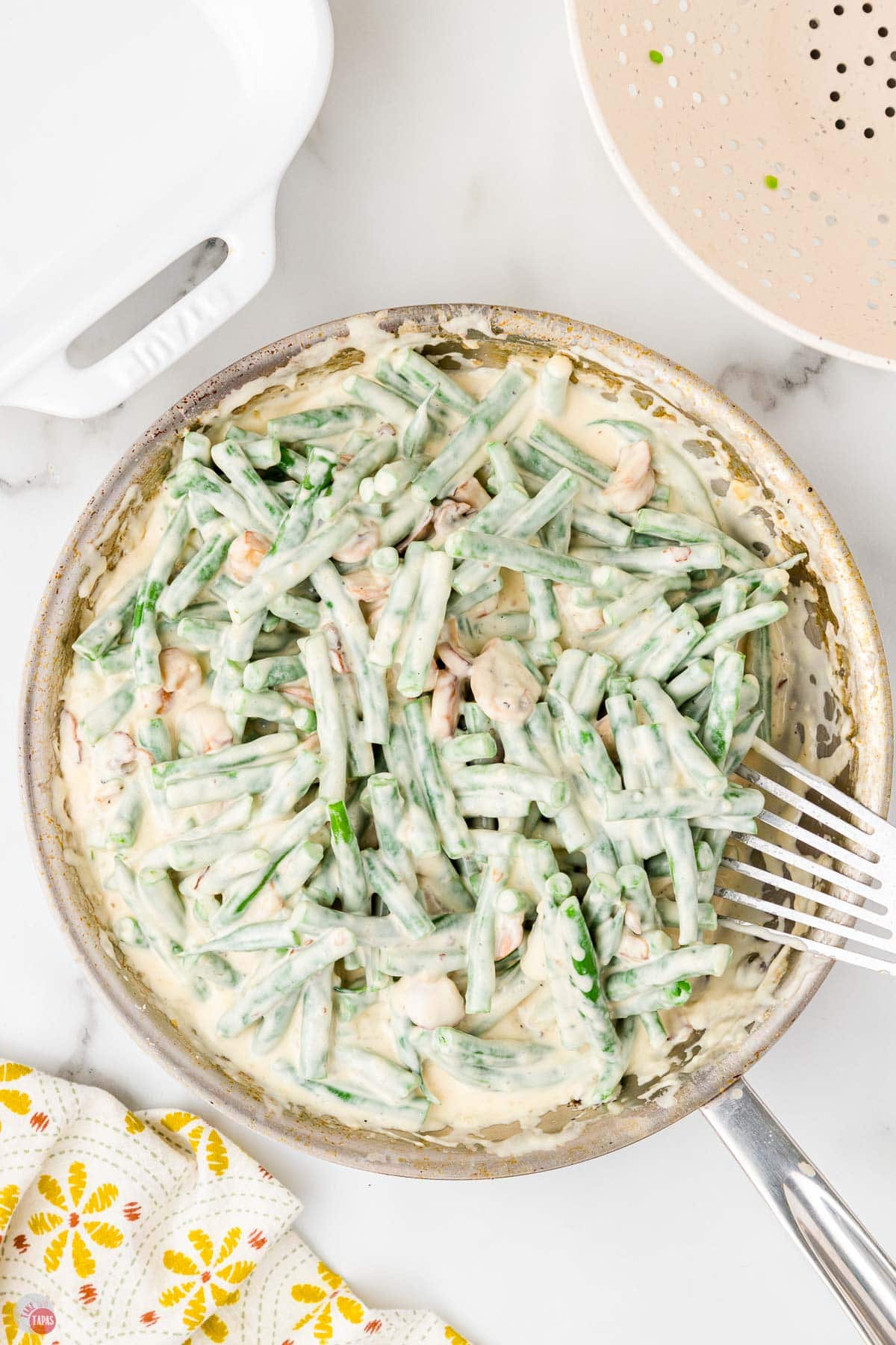 skillet of green beans being mixed into a mushroom gravy