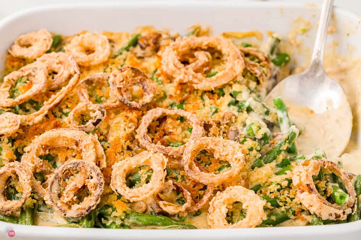 onion rings and green beans being scooped out of dish