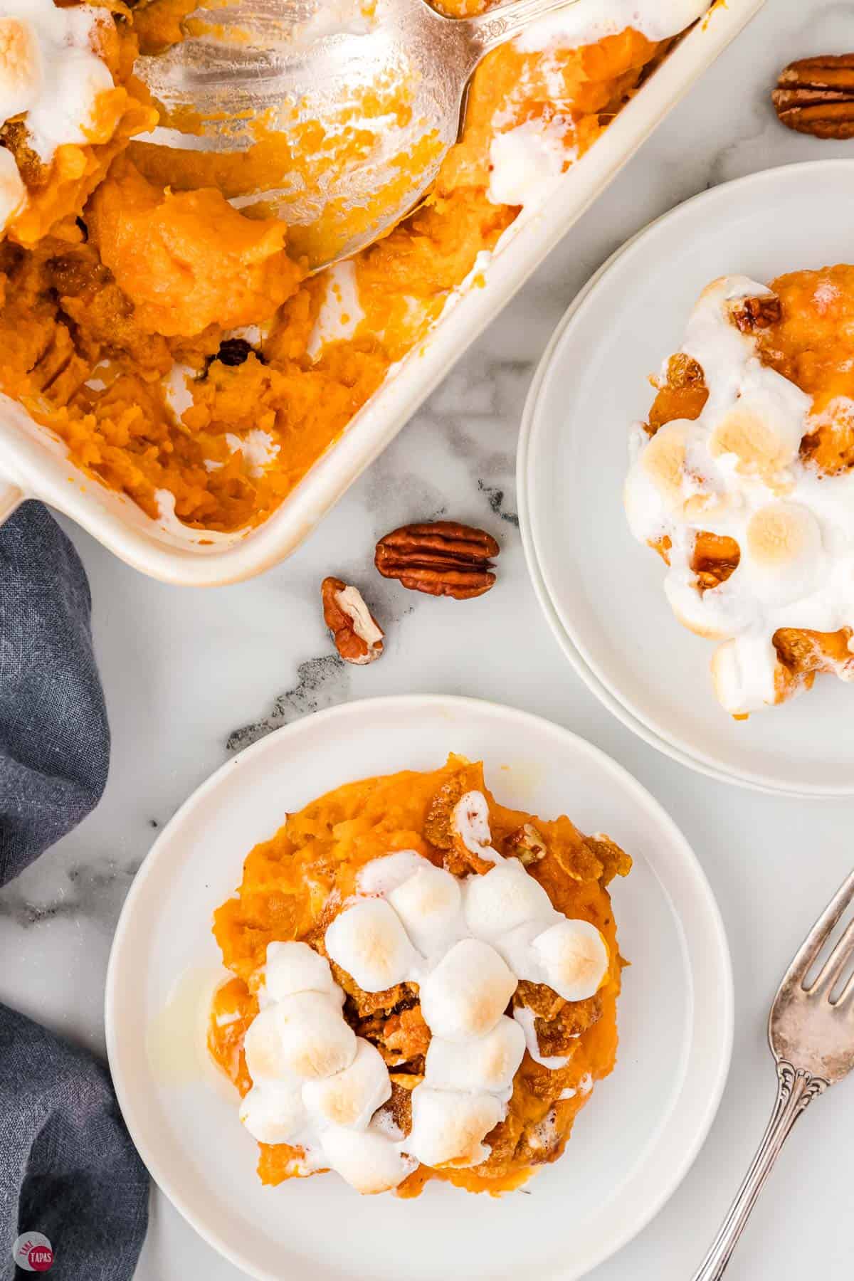 two small white plates with scoops of sweet potatoes next to a casserole in a dish with a scoop missing