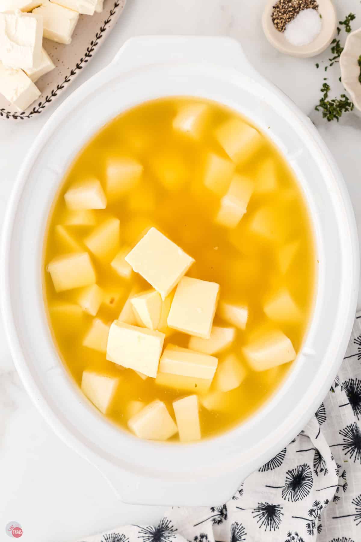 diced potatoes and butter covered with broth in a white bowl