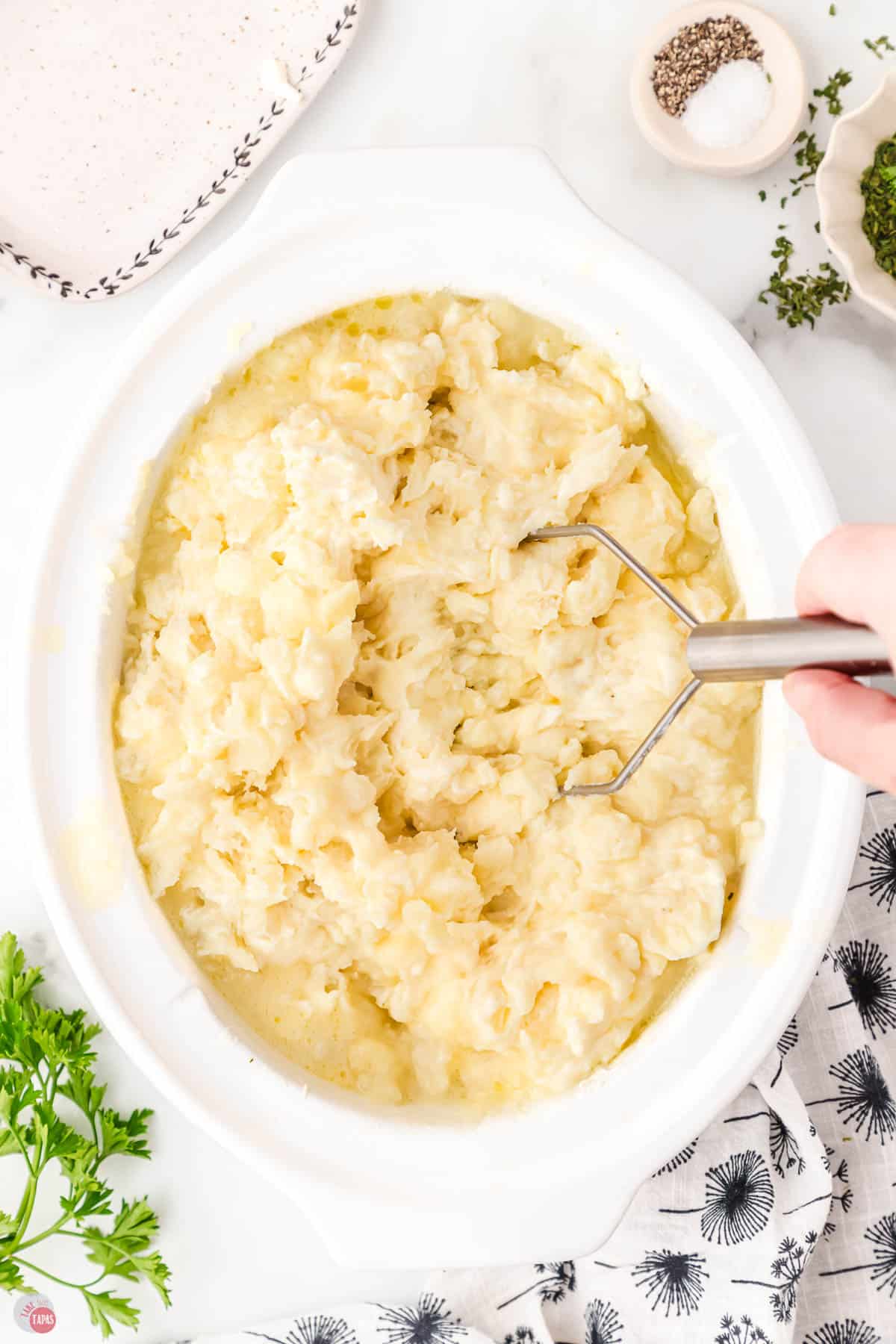hand mashed boiled potatoes in a white crock pot