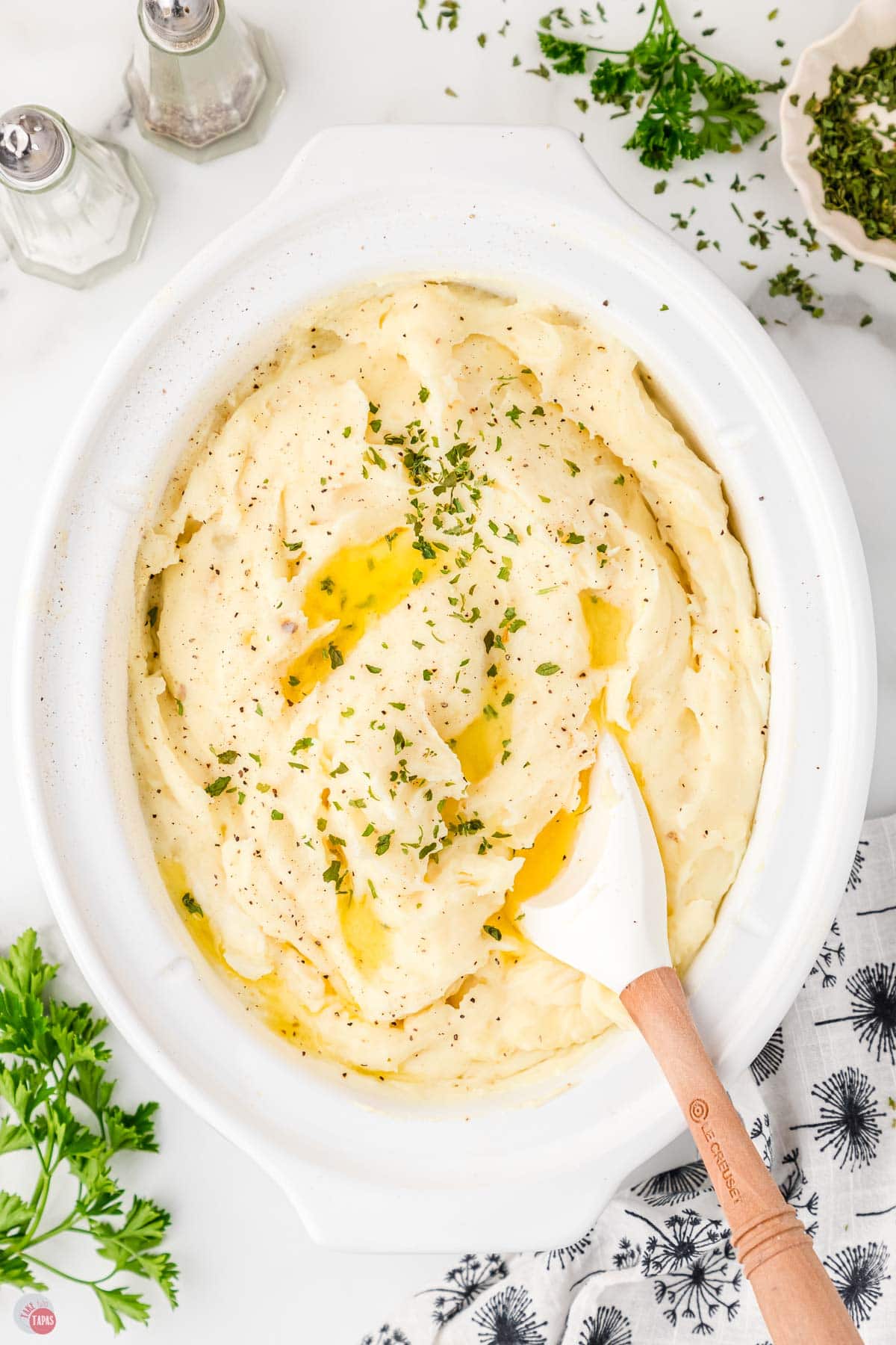 white slow cooker full of mashed potatoes with a spatula in it