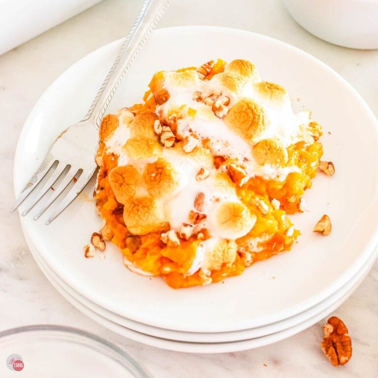 serving of sweet potato casserole on a stack of white plates with a fork on it