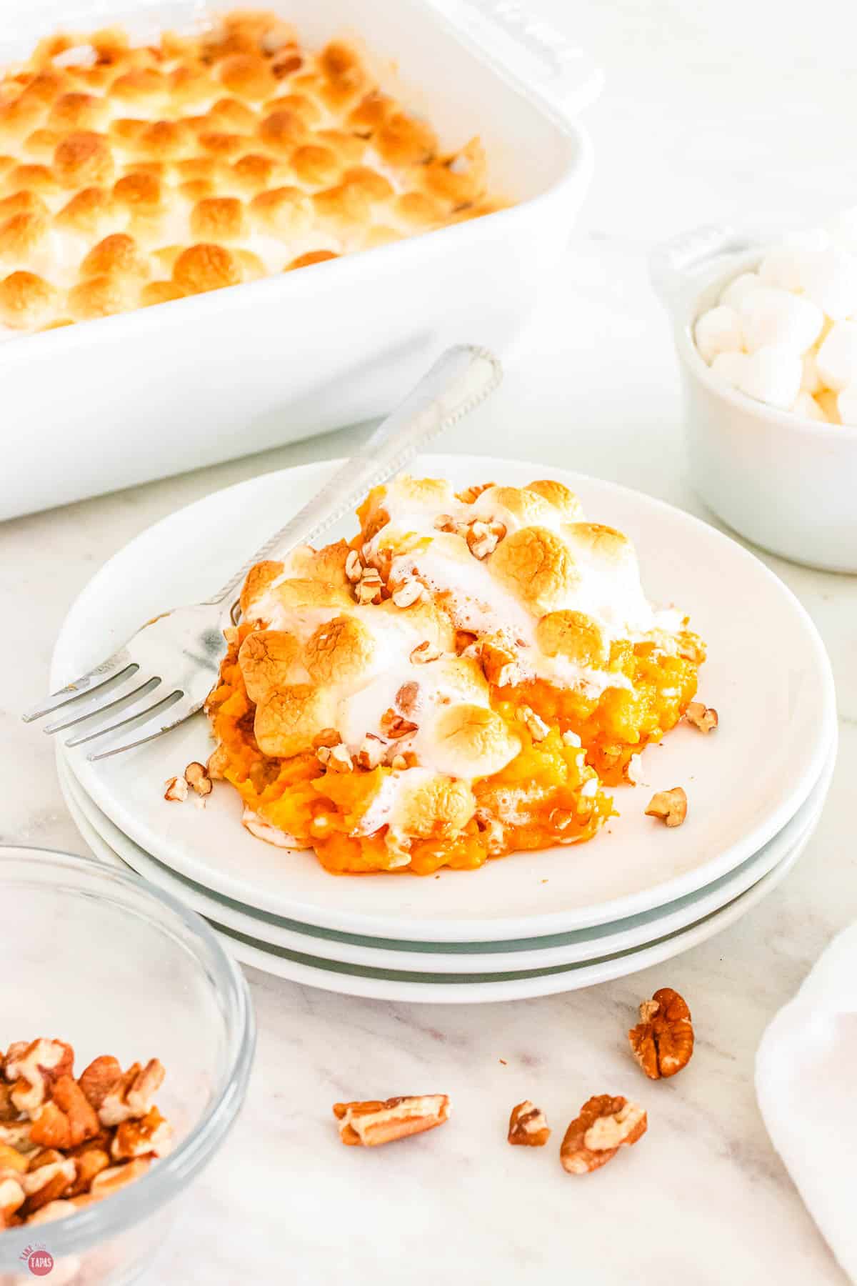 stack of white plates with a scoop of sweet potato casserole and a fork
