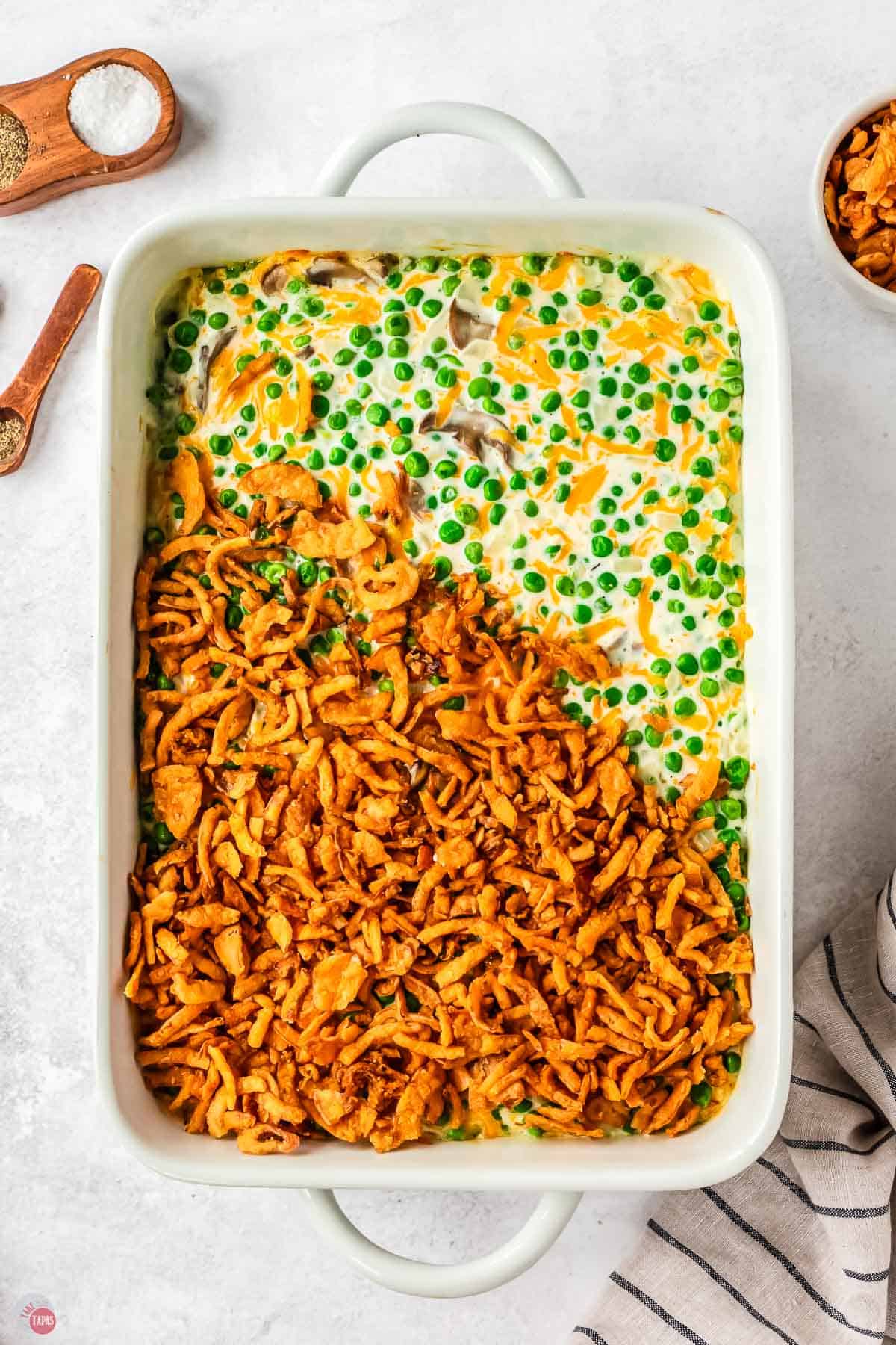 pea casserole in a white dish partially covered with fried onions