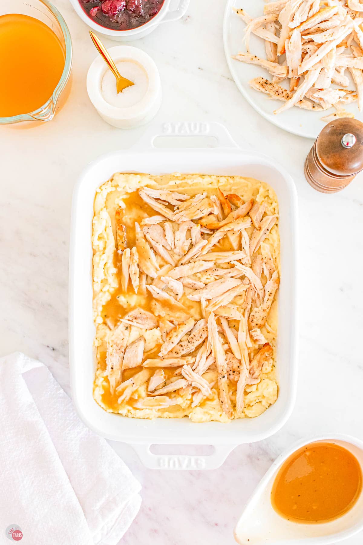 casserole dish with a layer of mashed potatoes and shredded turkey on top