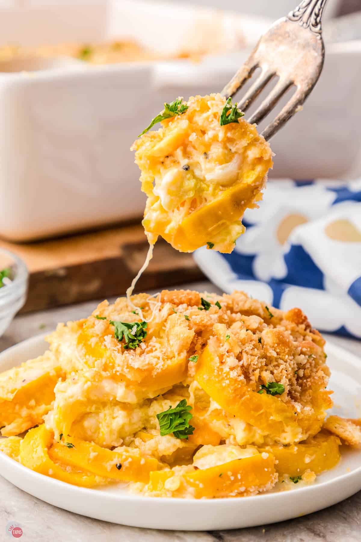 white plate with squash casserole on it and a fork lifting a bite