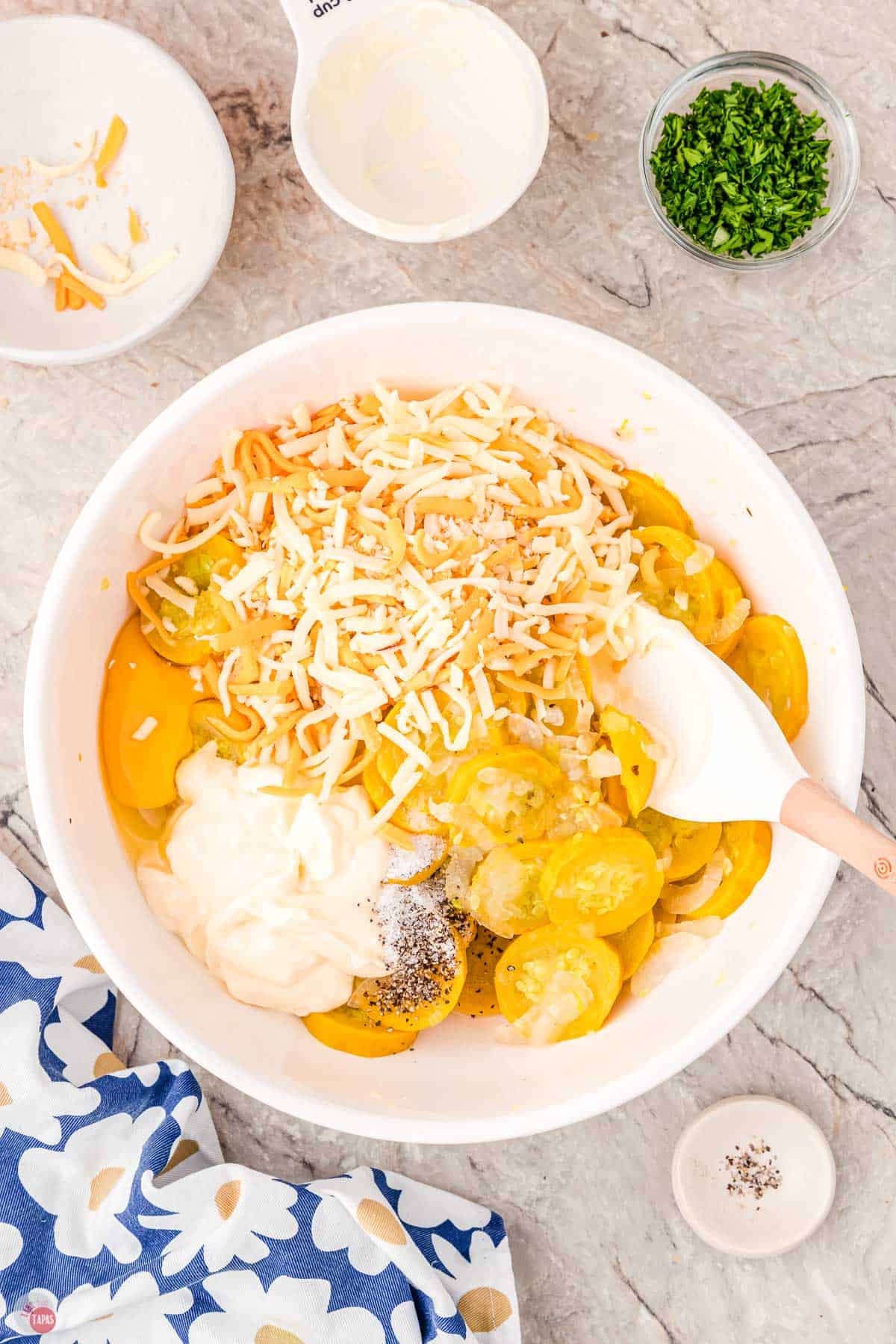 white bowl of squash with mayo and shredded cheese