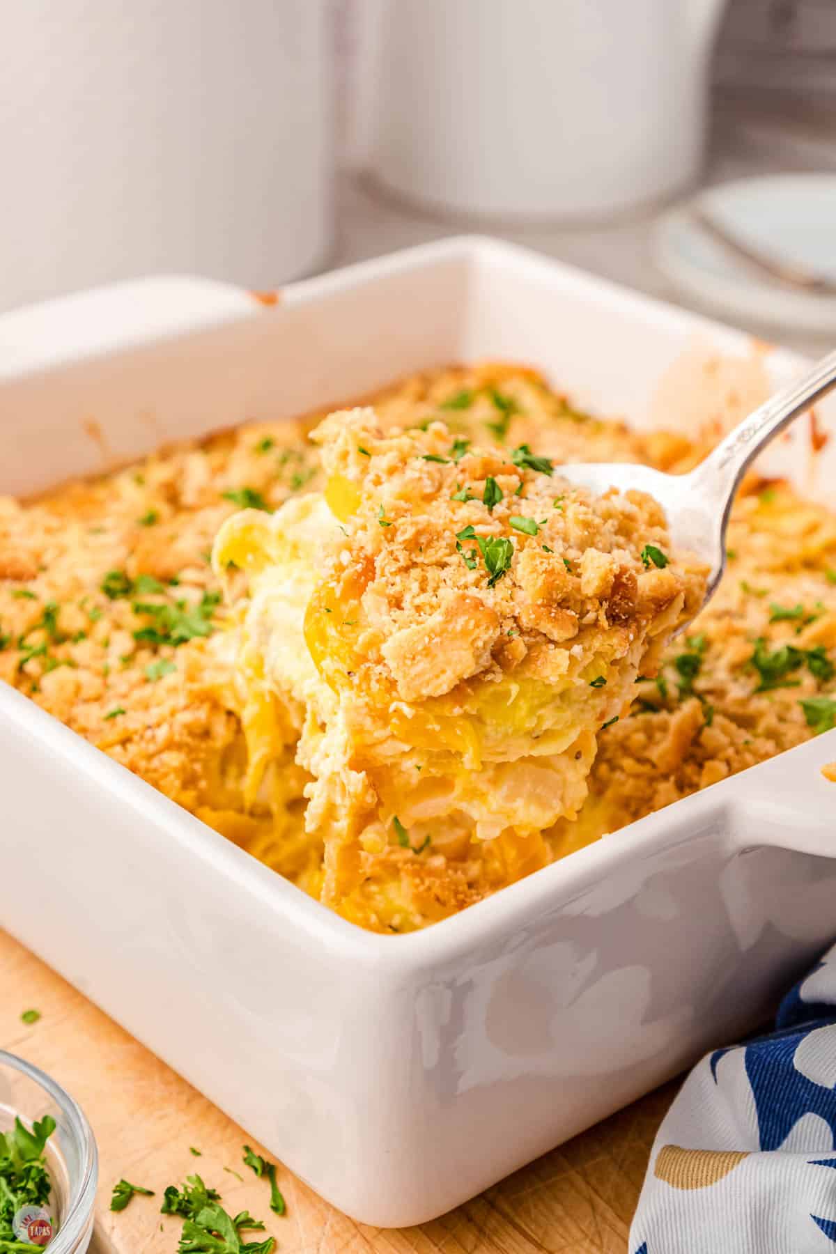 spoon scooping casserole out of a white dish