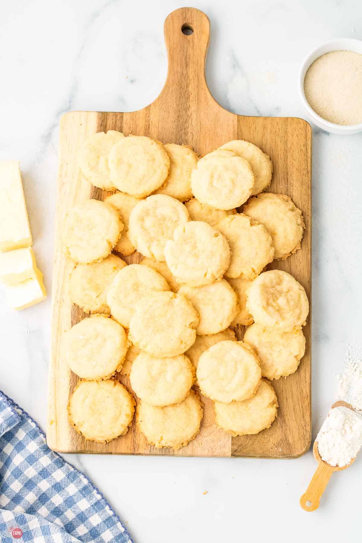 wood cutting board with pile of cookies on it