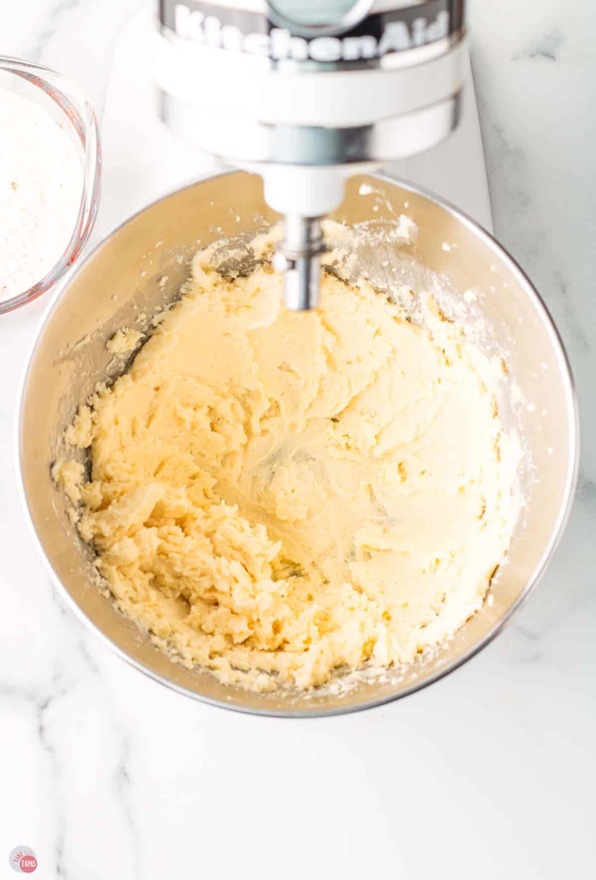 butter and sugar being creamed together in a metal mixing bowl