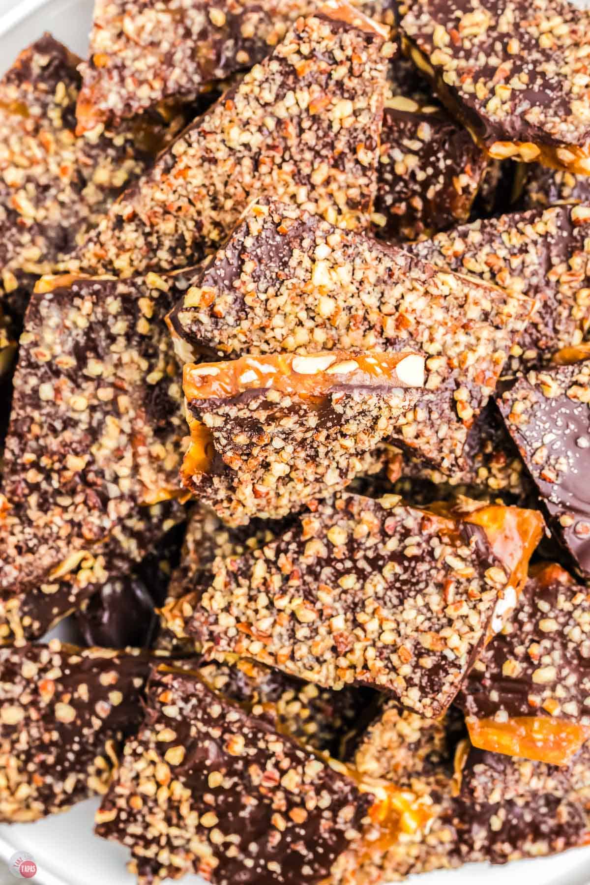 close up of plate of toffee with chocolate and pecans