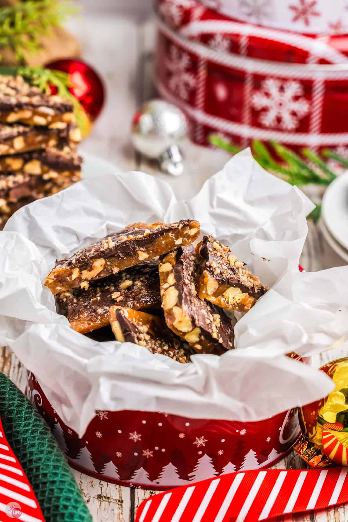 red tin with parchment paper and filled with pieces of toffee candy
