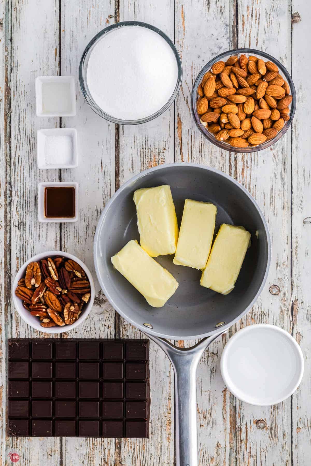 butter in a pot next to two bowls of sugar and almonds