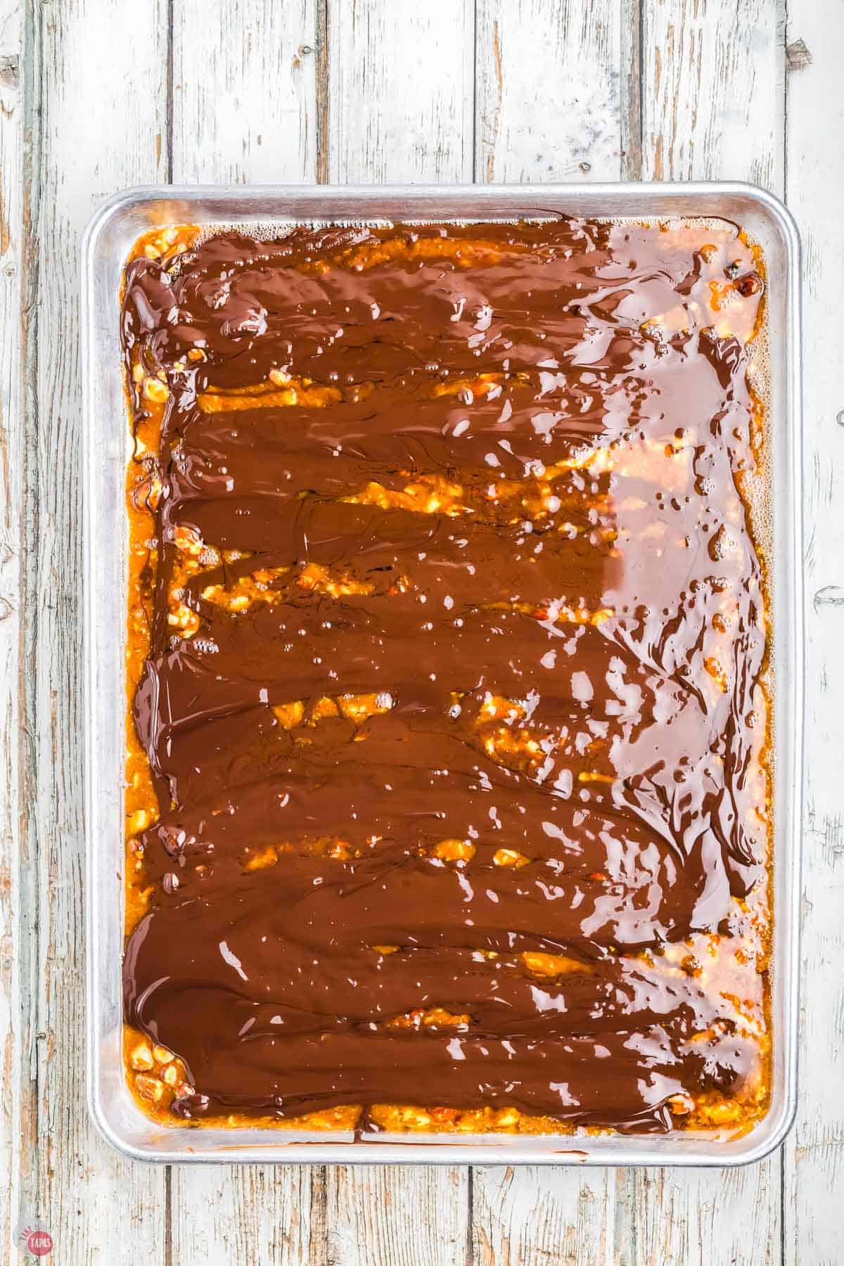 melted chocolate spread on top of toffee on a baking sheet