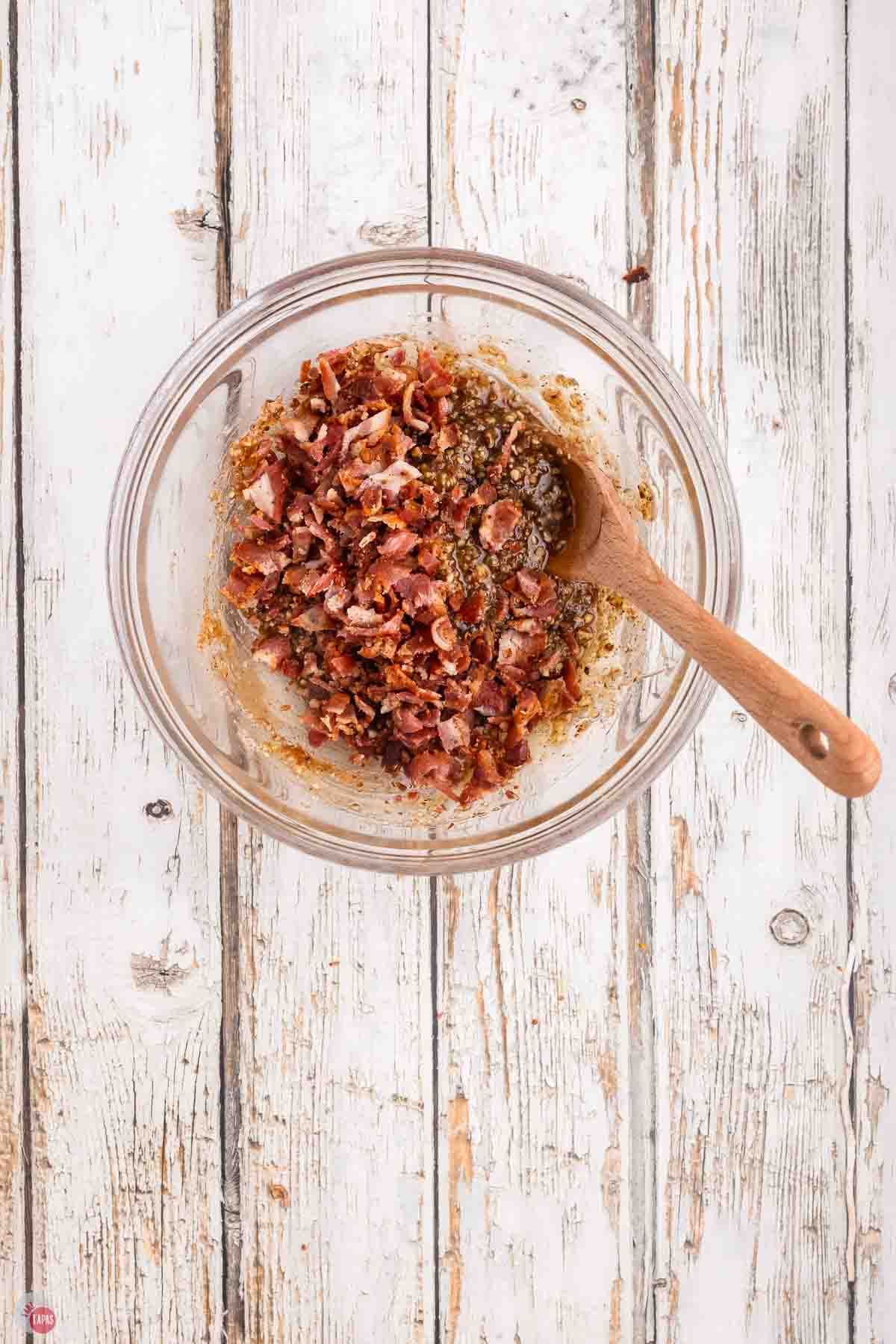 clear bowl with bacon jam and a wood spoon