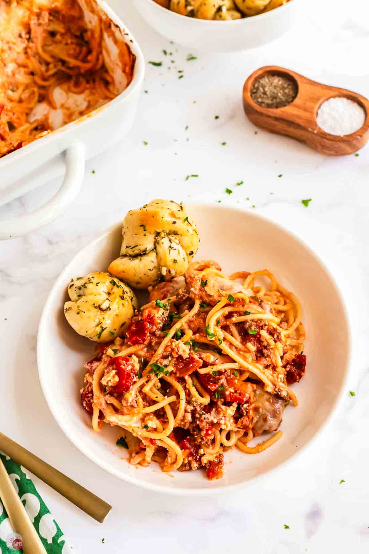 white bowl of spaghetti with two garlic knots on it