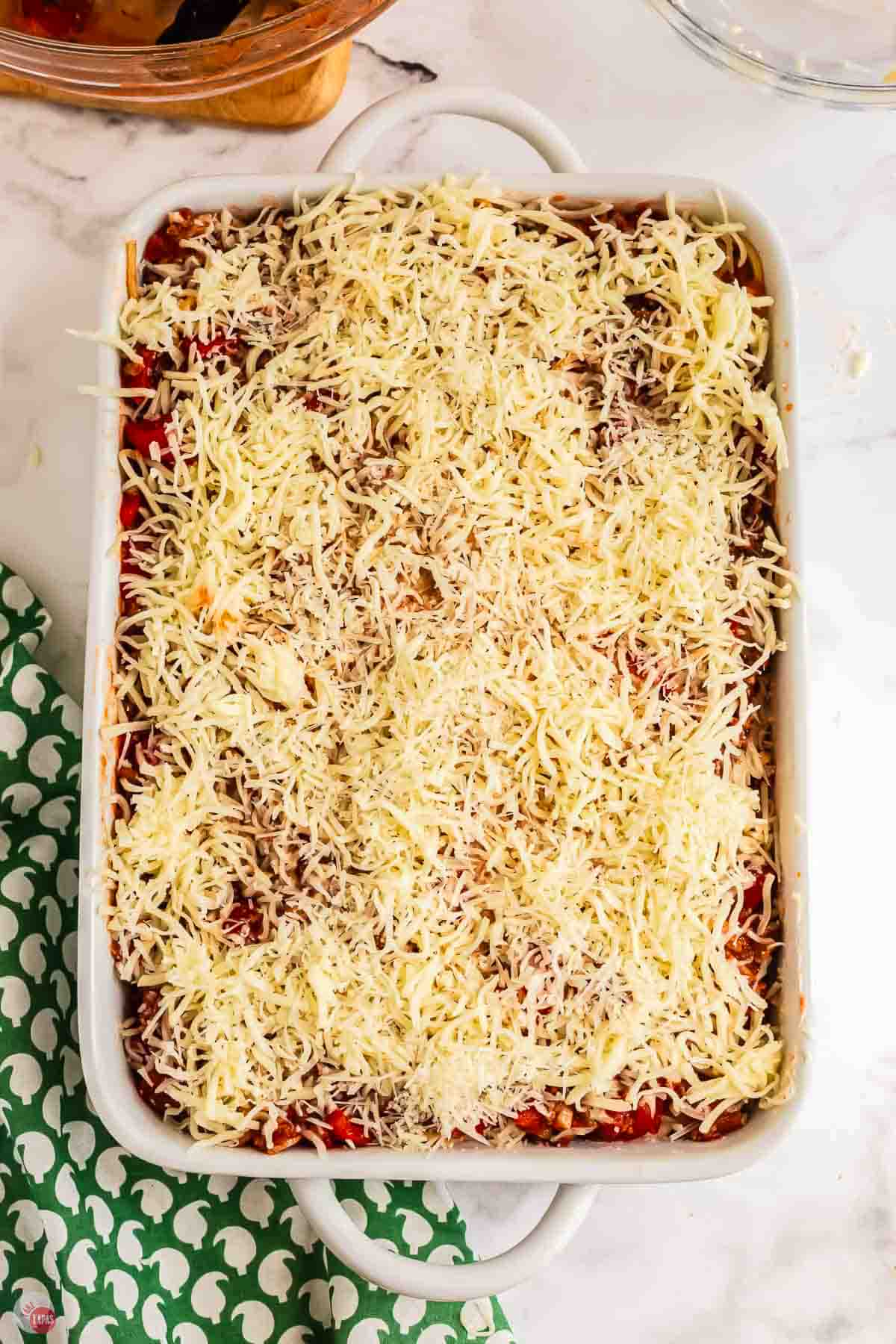 unbaked spaghetti casserole with cheese on top