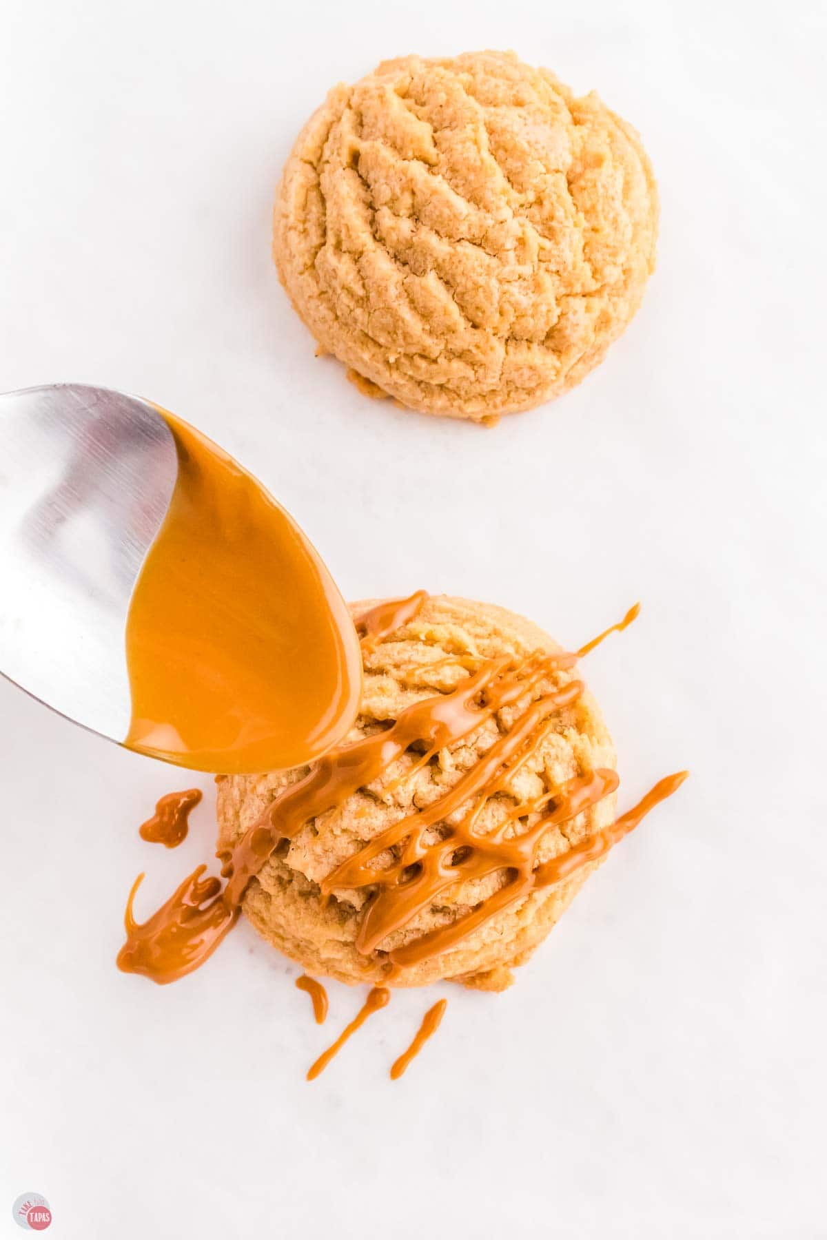spoon drizzling melted biscoff spread over the top of a cookie