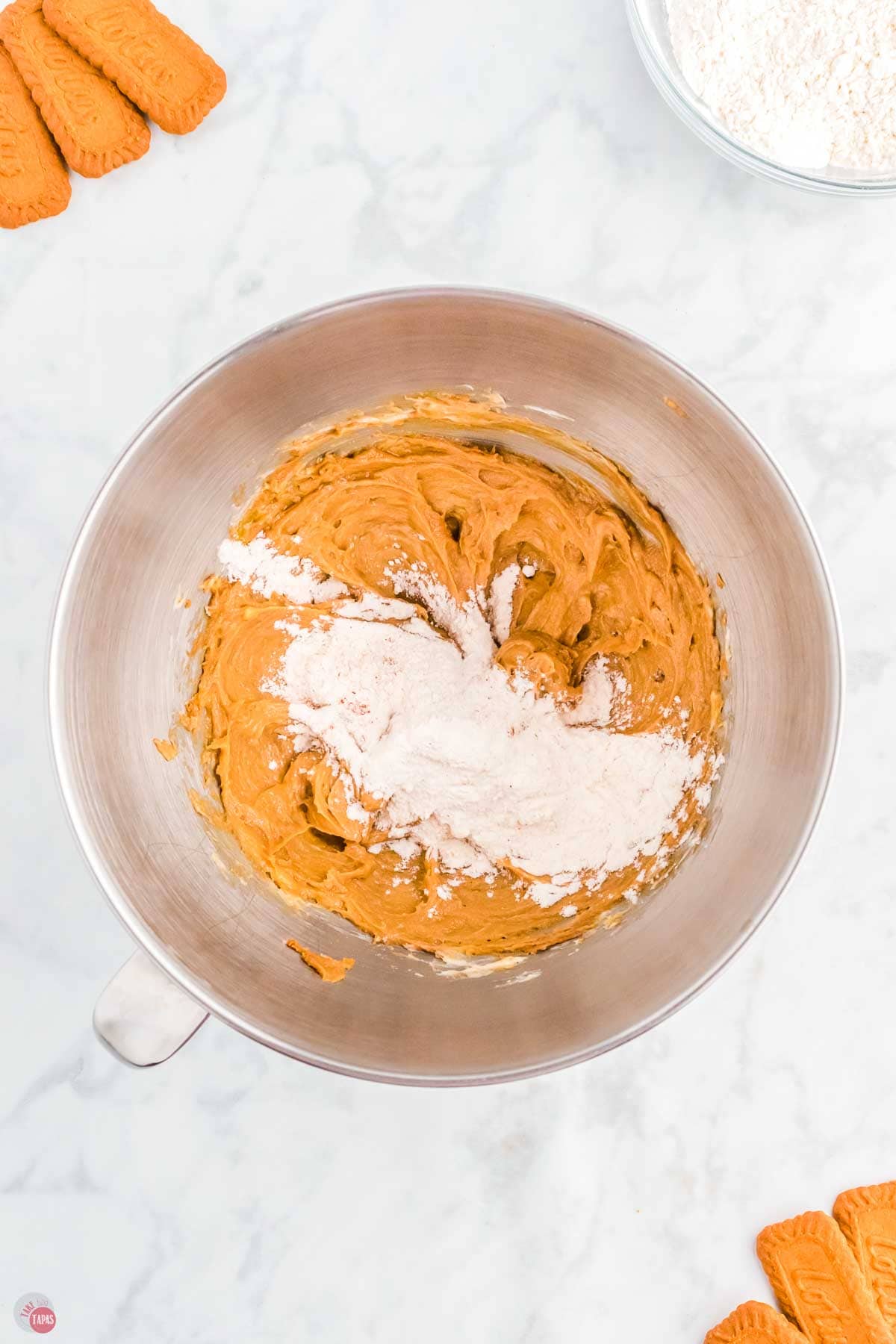 flour on top of cookie dough in a silver mixing bowl