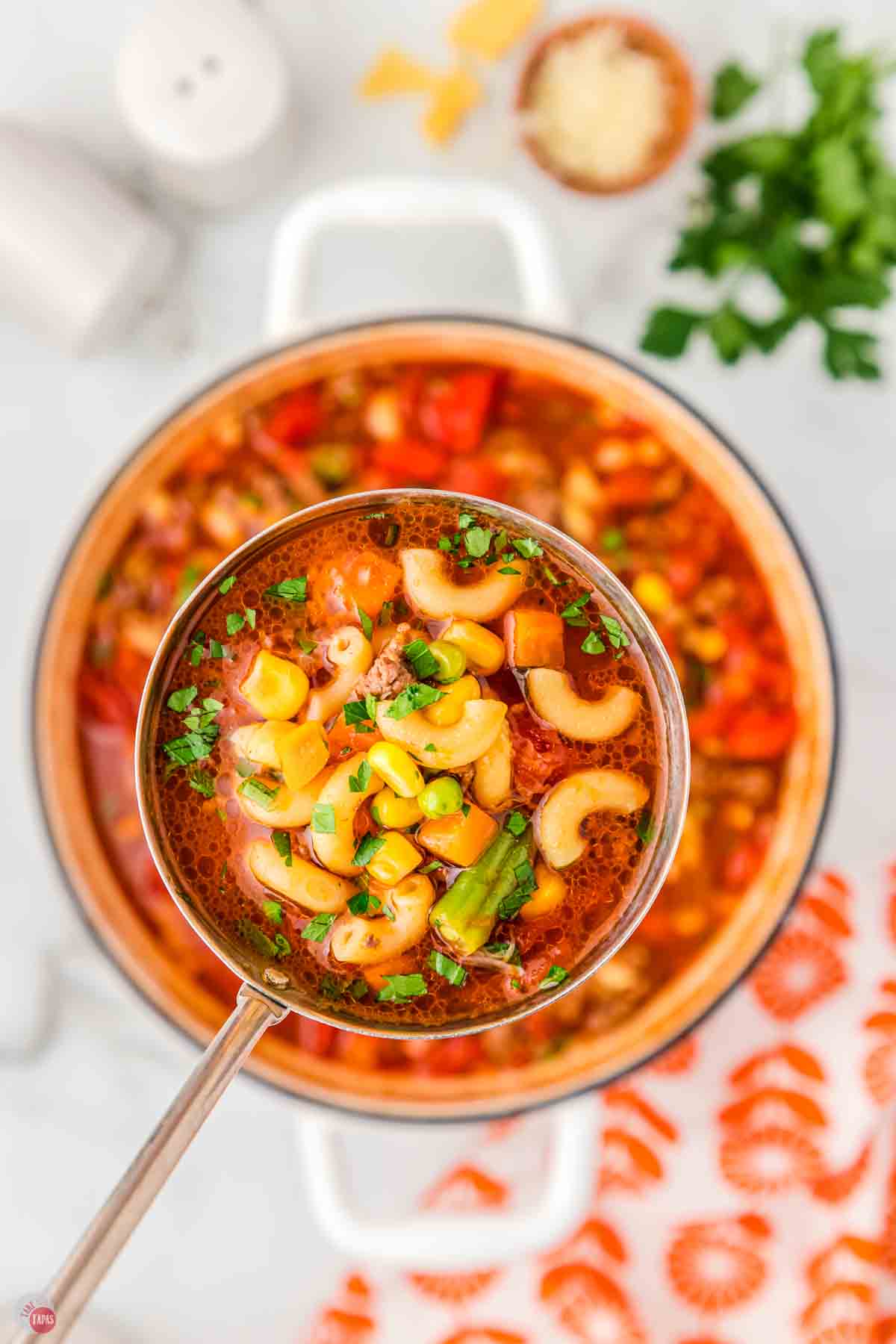 close up of ladle of soup with macaroni in it