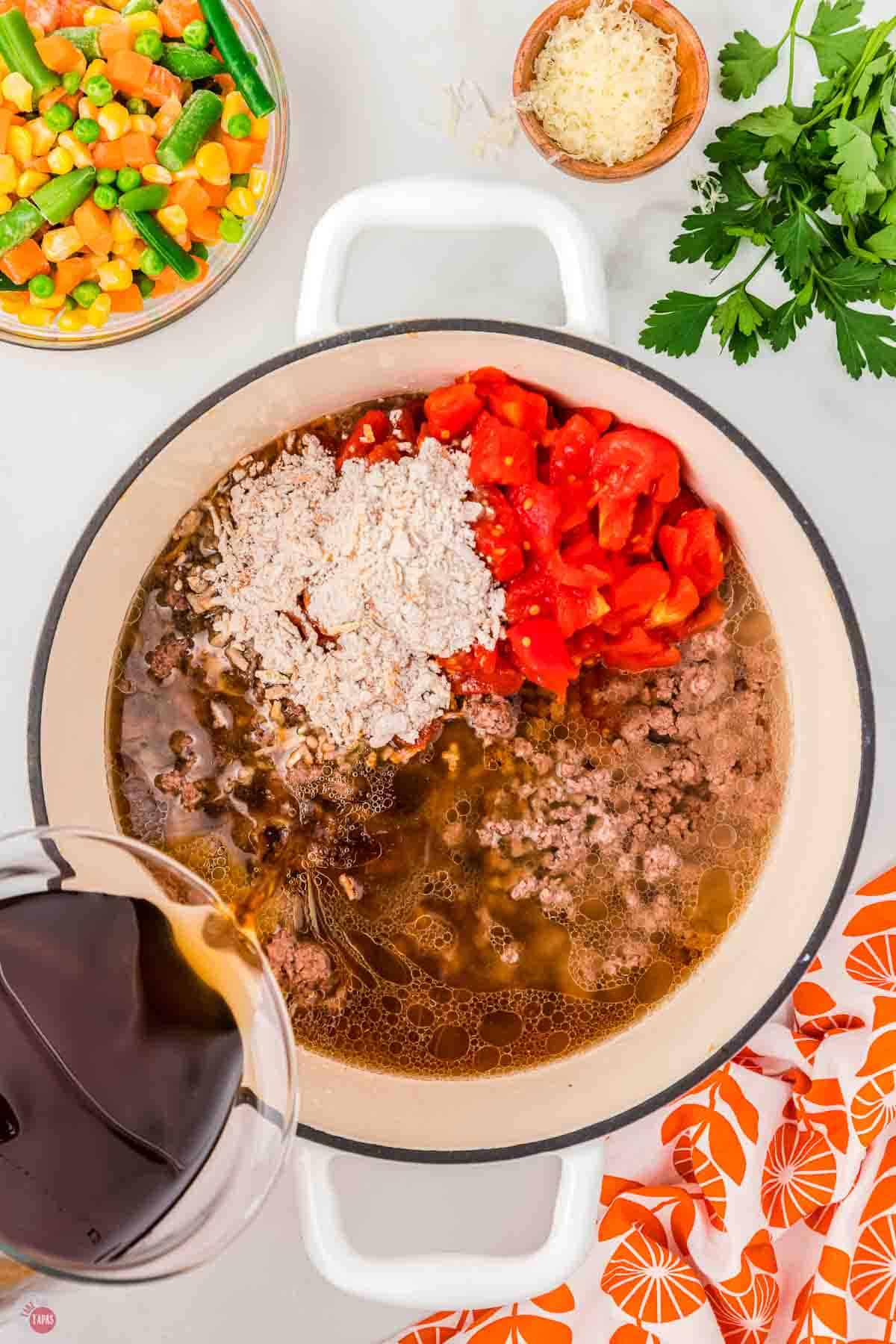 pot with ground beef tomatoes, soup mix, and beef broth