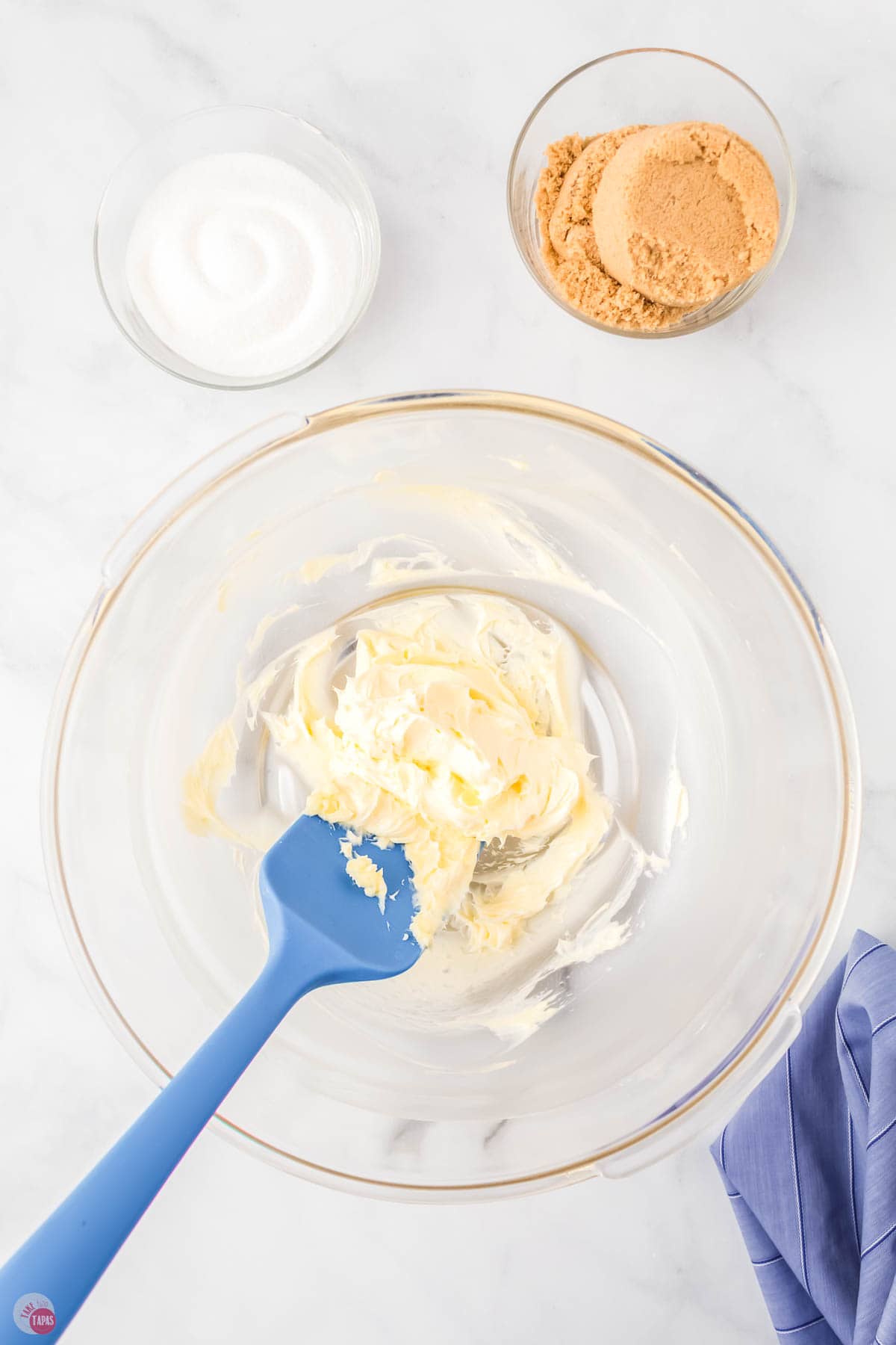 whipped butter in a clear bowl with a blue spatula