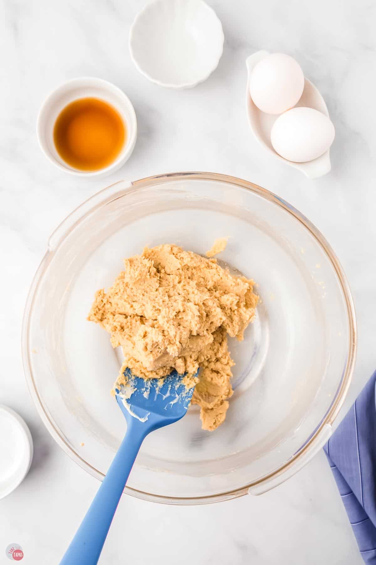 sugar and butter in a clear bowl with a blue spatula