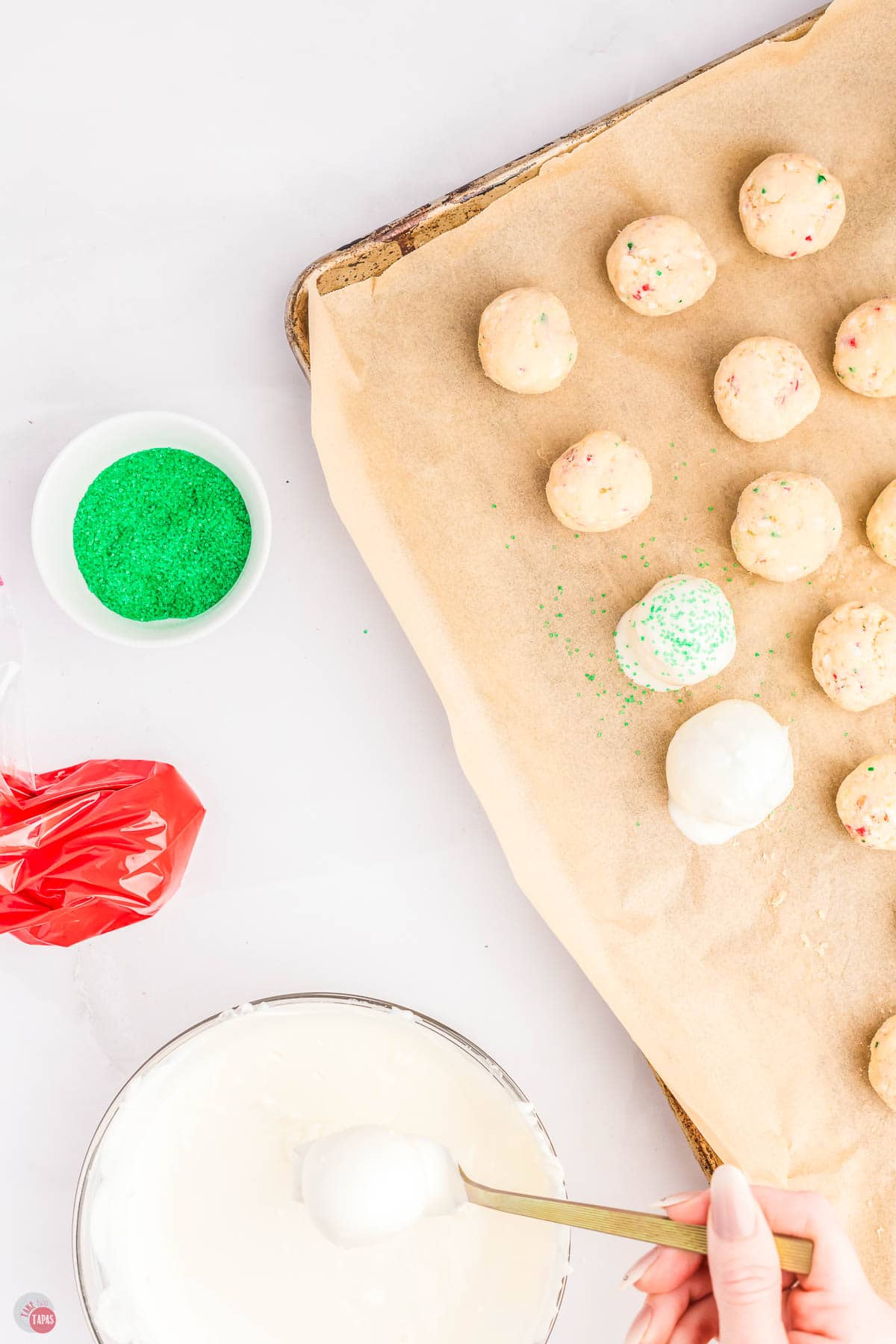 cake balls being dipped in white chocolate on a baking sheet