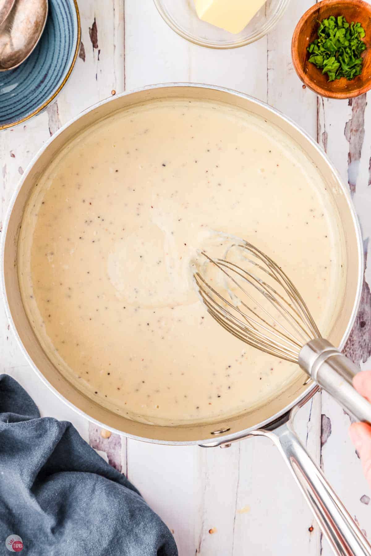 pot with cream sauce and a whisk