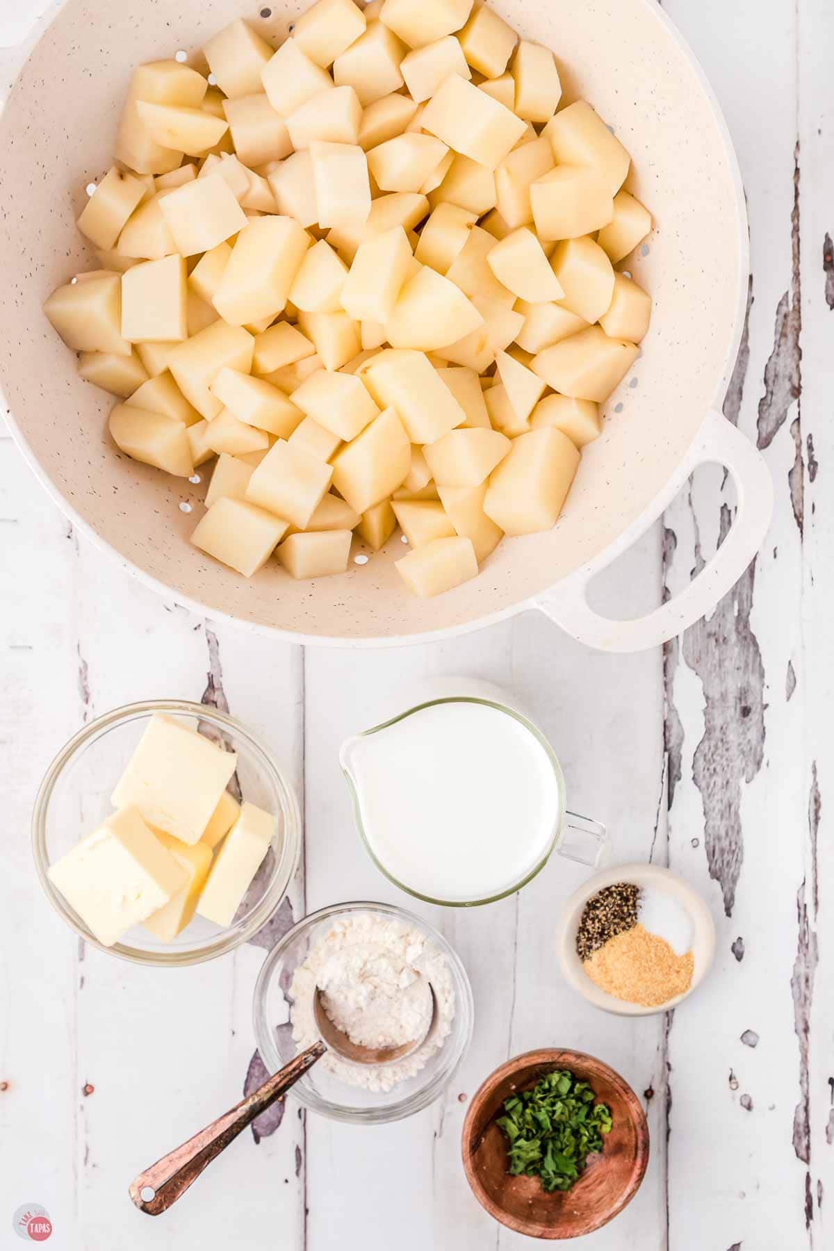 diced potatoes in a white colander with bowls of butter and milk