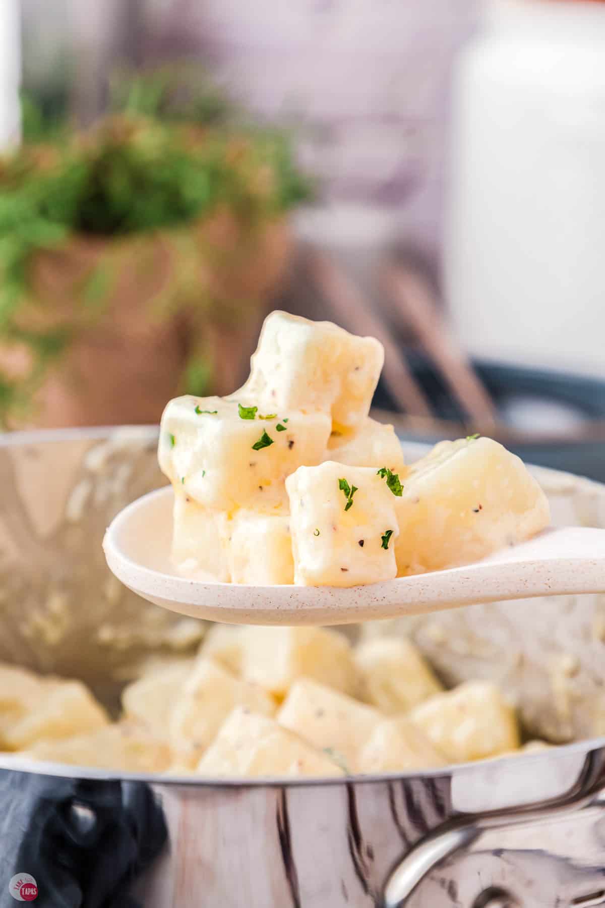 white spoon with a small stack of diced potatoes on it