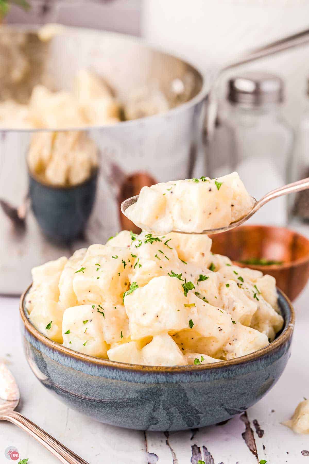 blue bowl with diced potatoes in it and a spoon hovering above it