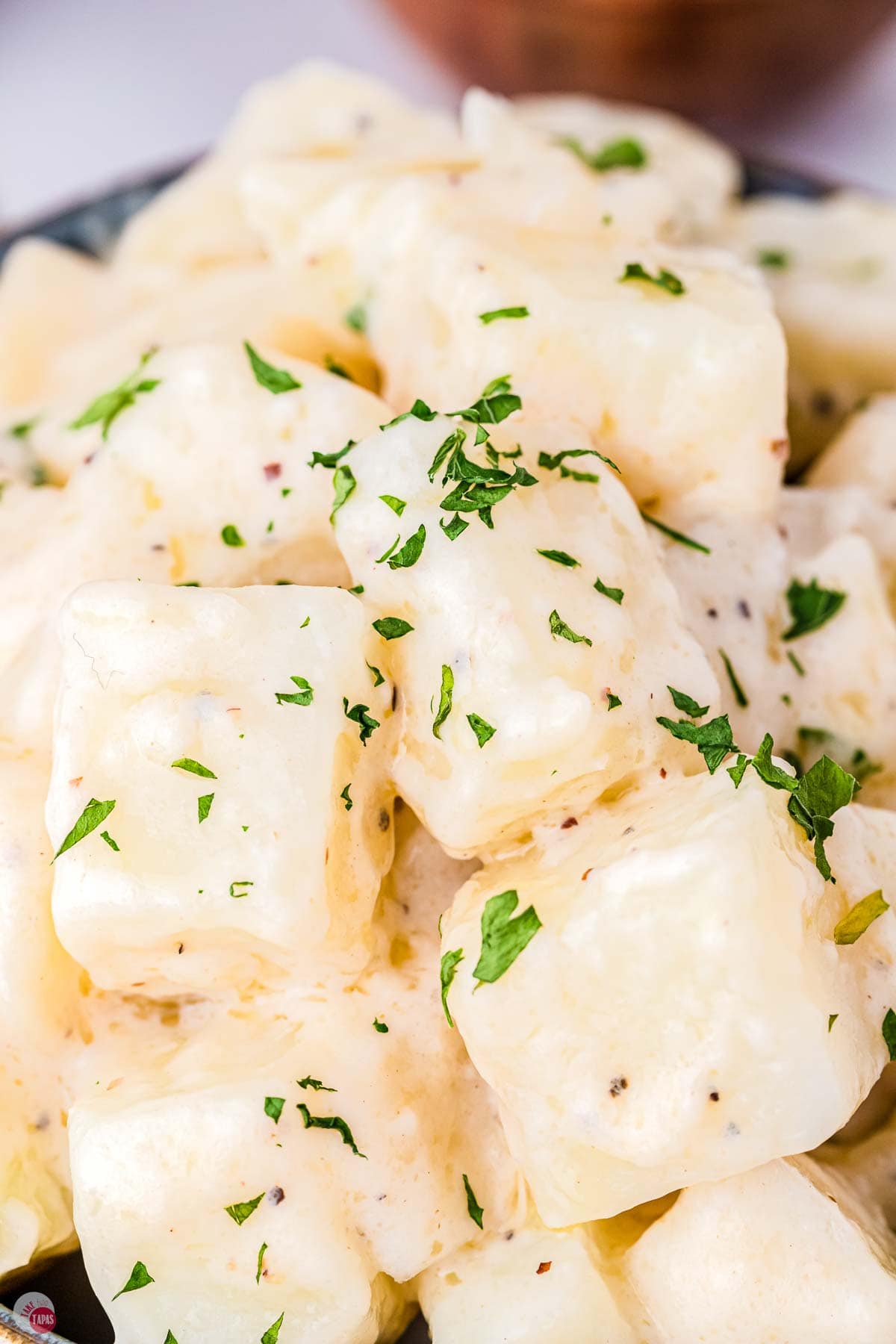 close up of diced potatoes with cream sauce and chopped parsley