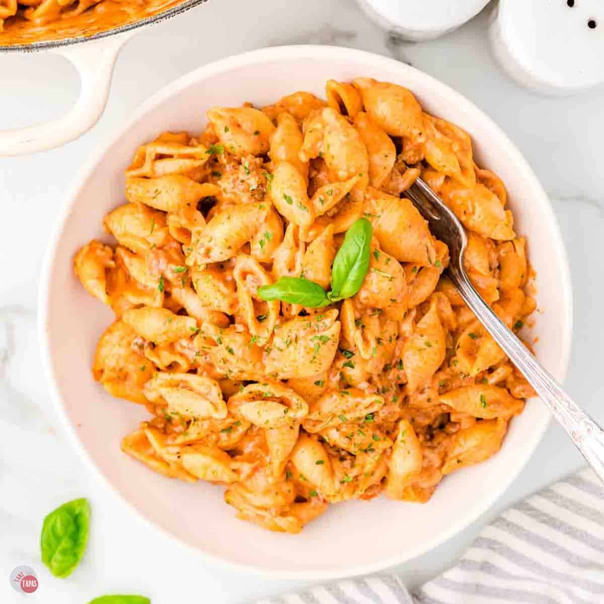 white plate of pasta shells with basil on top