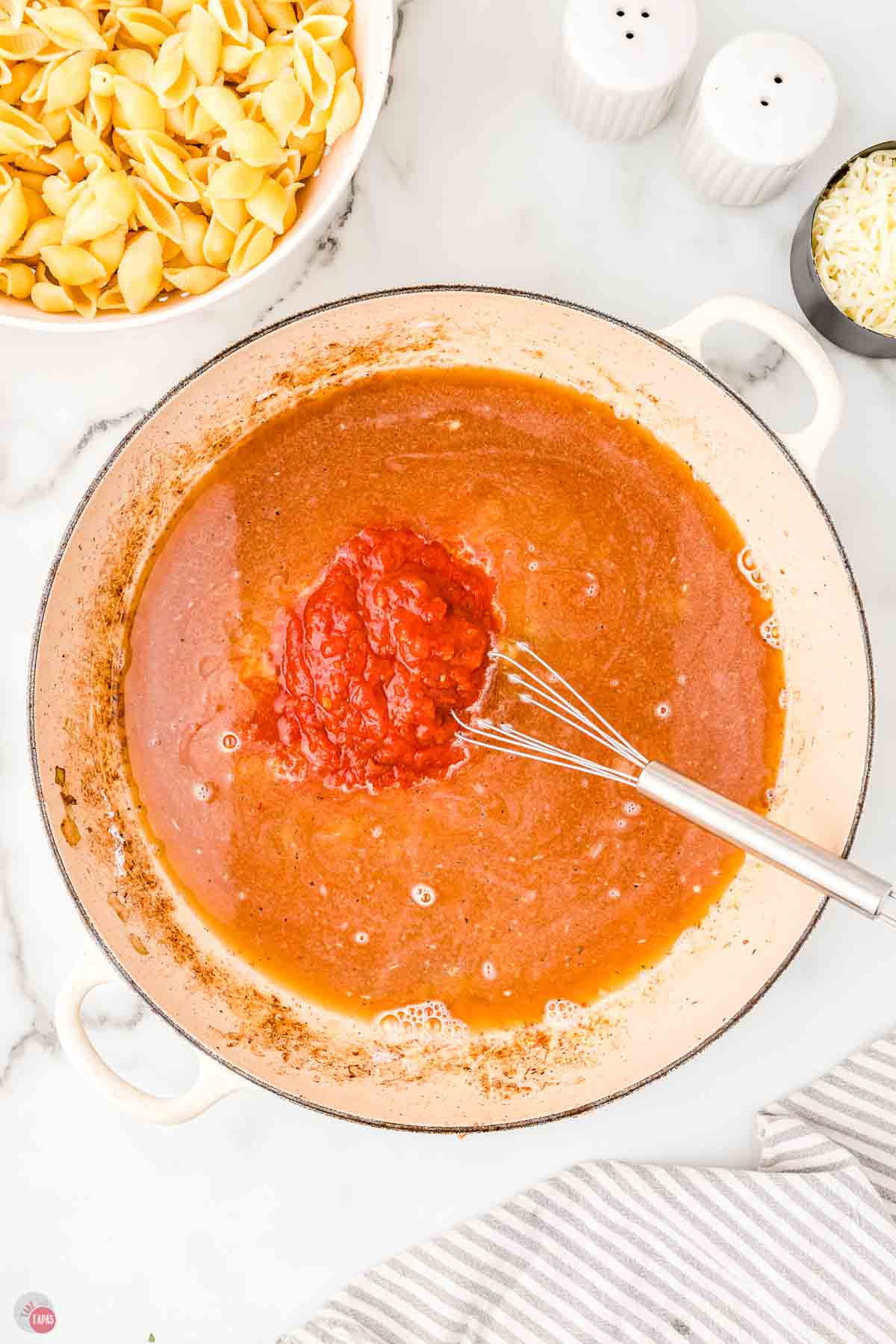 broth and tomatoes being whisked in a pot