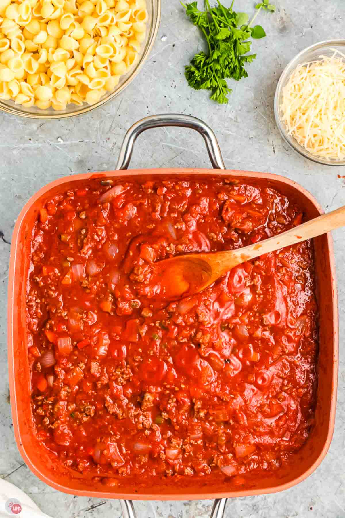 meat sauce in a skillet with a wood spoon