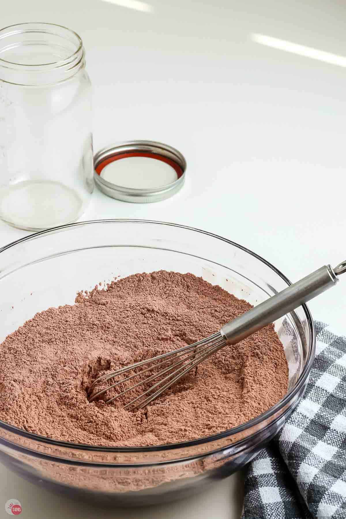 bowl of hot chocolate mix with a whisk and a checkered napkin