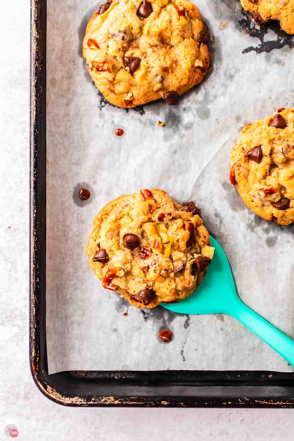 baked cookie with a blue spatula over a cookie sheet