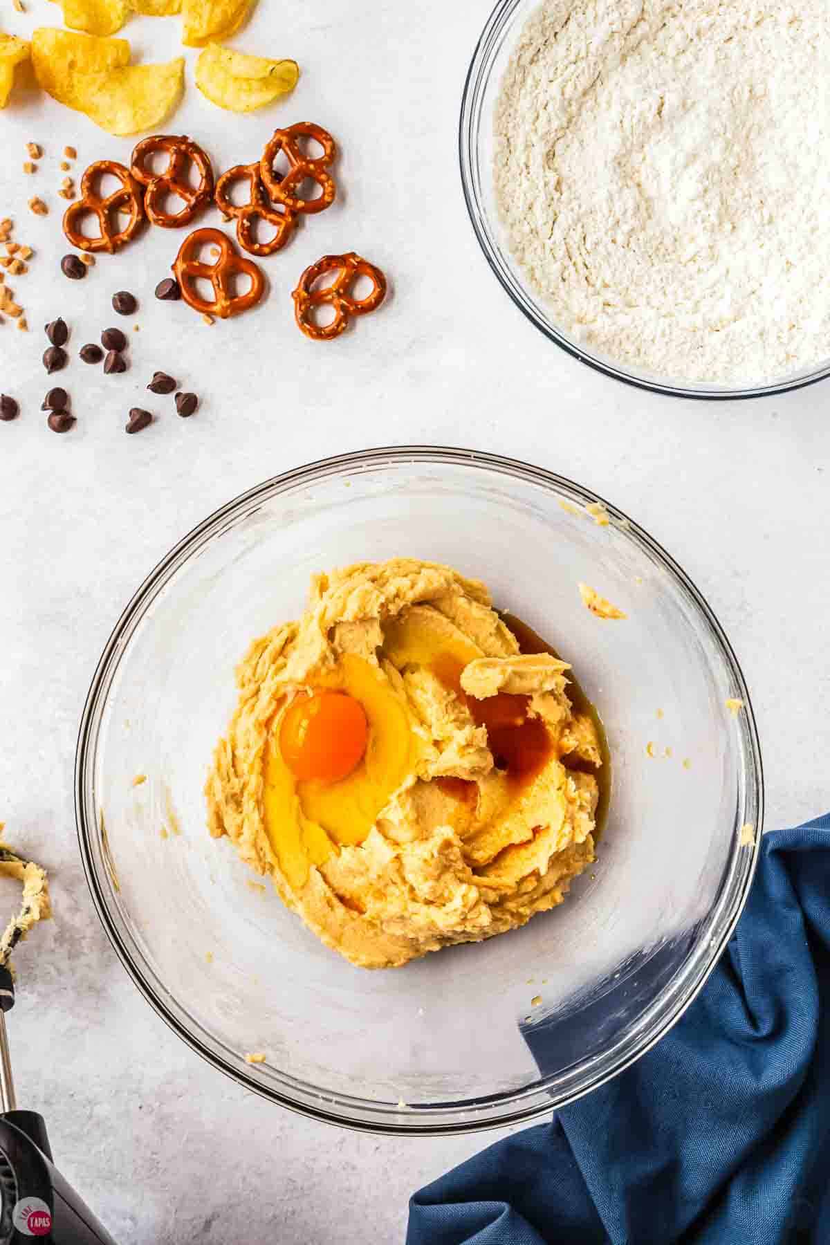 cookie batter with eggs and vanilla on top of it in a clear bowl