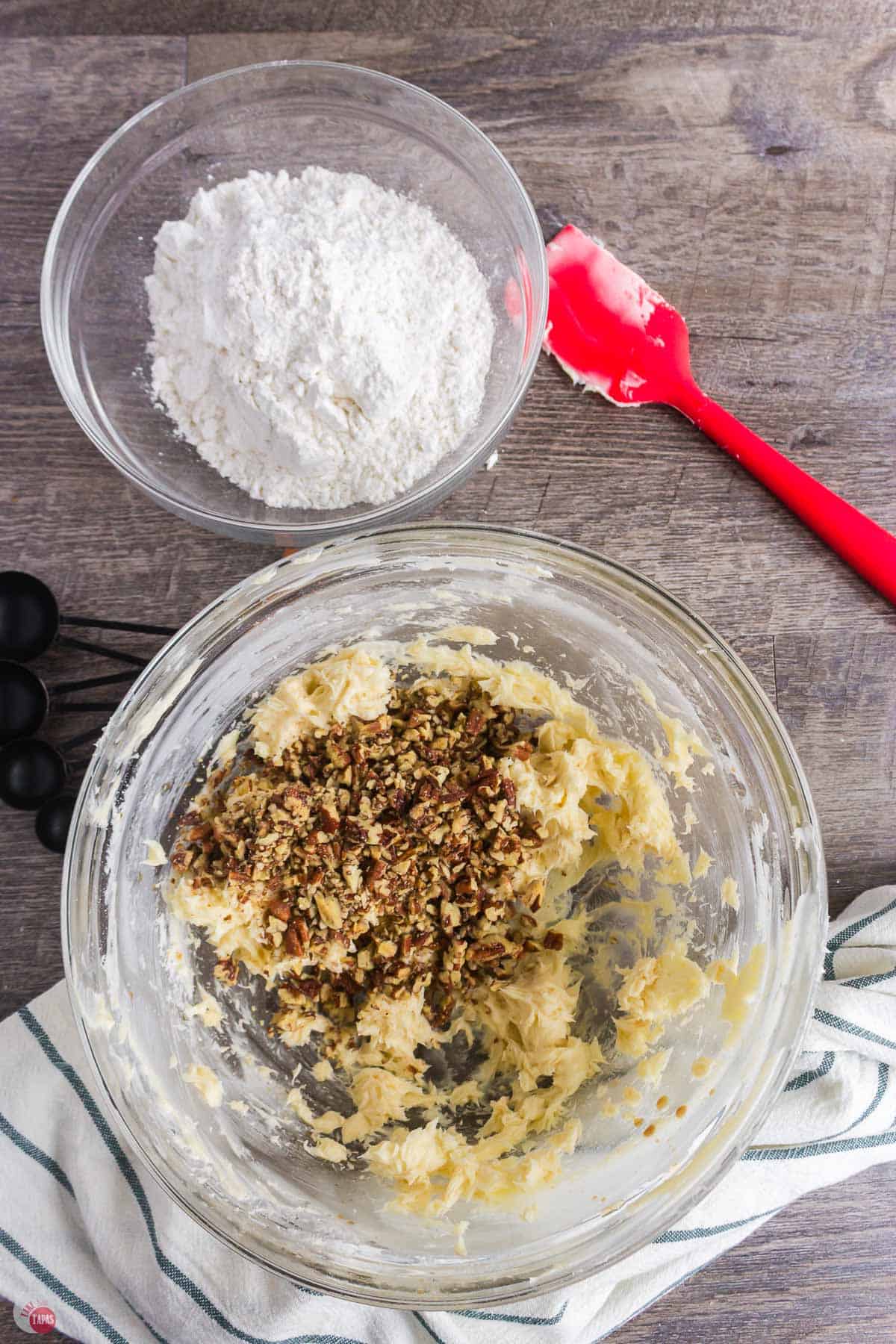 butter and pecans mixing in a bowl with a red spatula