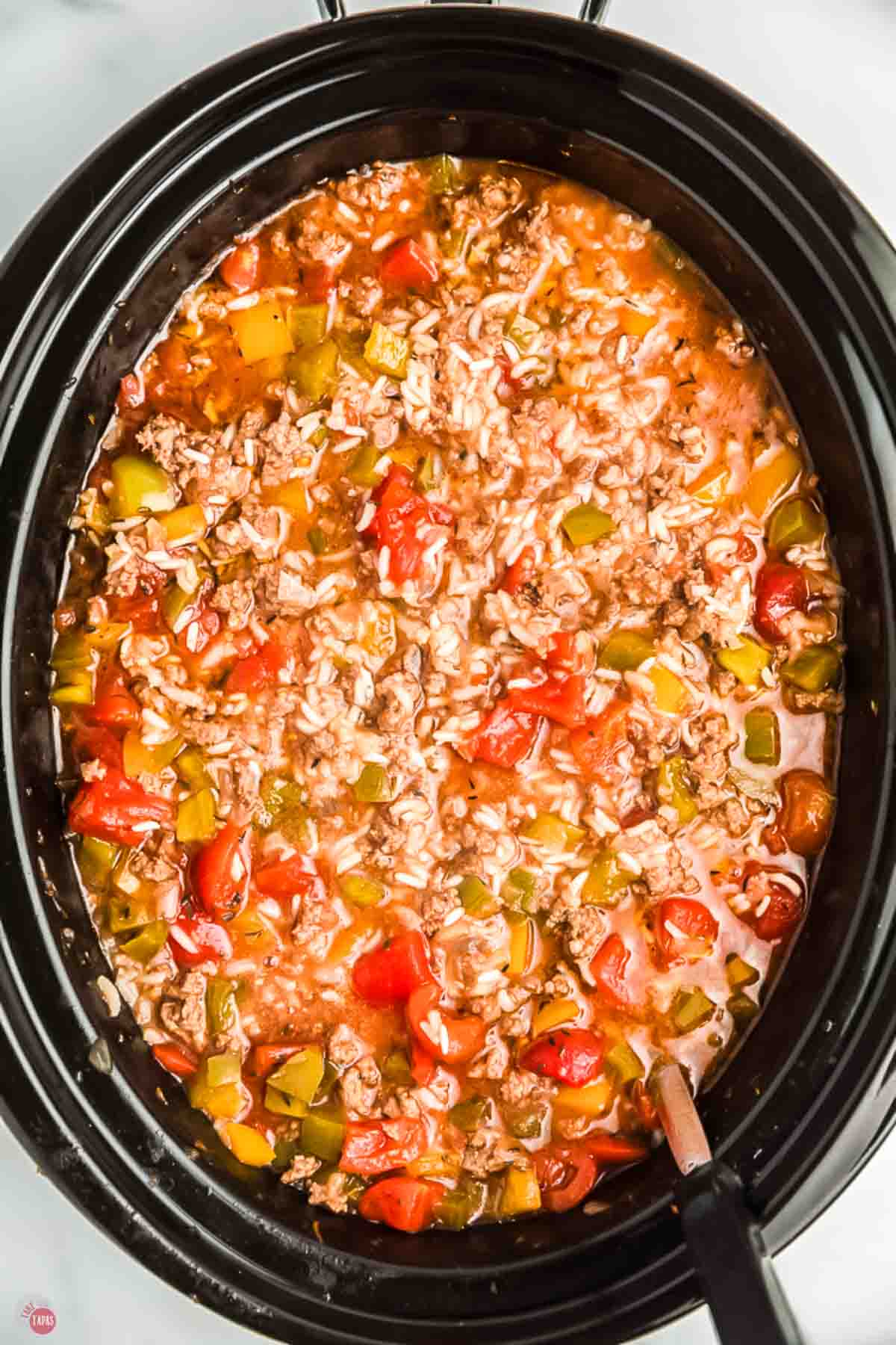 close up of black slow cooker with bell pepper soup in it